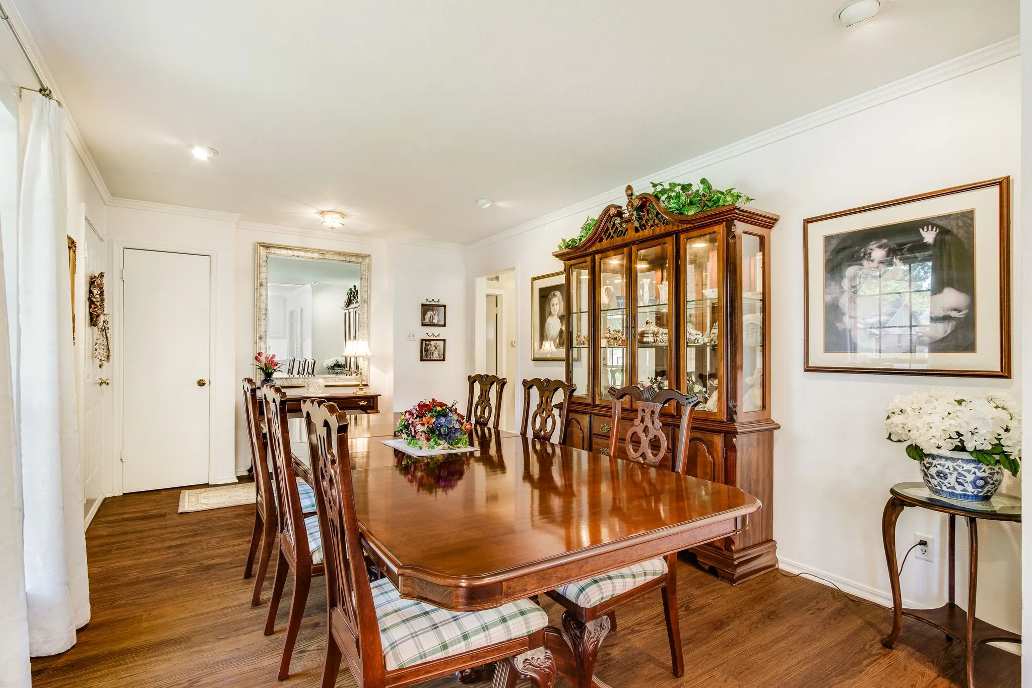 Dining space featuring wood-finish flooring, recessed lighting, white trim, crown molding, and a built-in display cabinet with glass doors