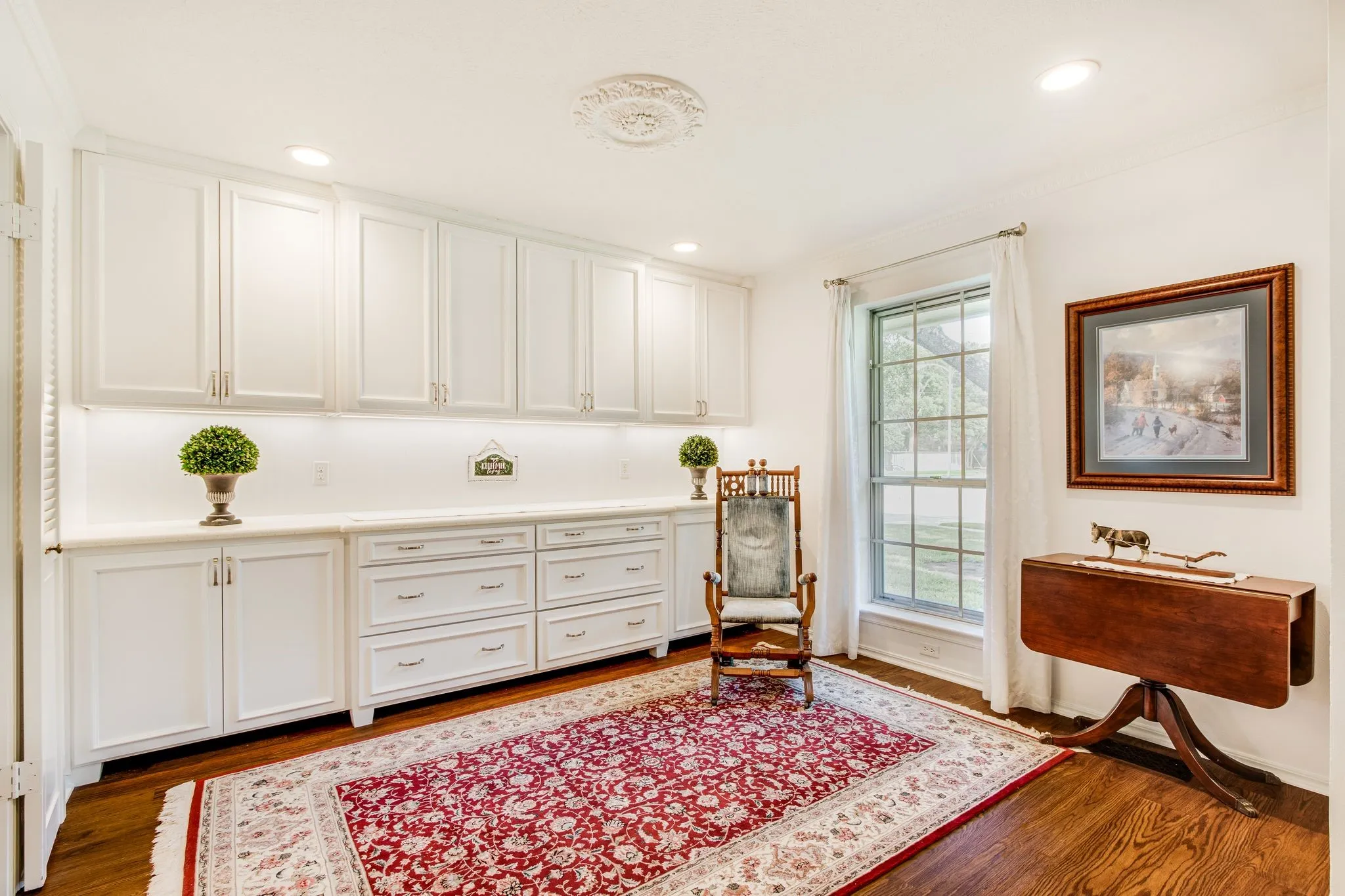 Built-in white cabinetry with under-cabinet lighting, a light-toned countertop, and wood-finish flooring