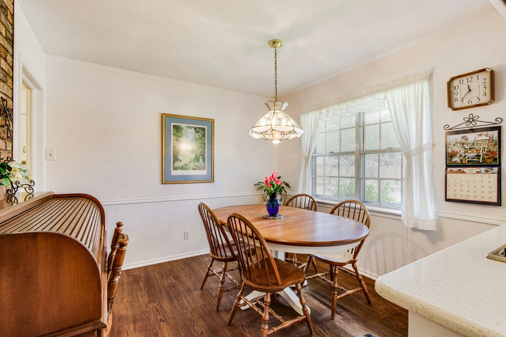 Dining area featuring dark wood-finish flooring, white wainscoting, and a central window with white​​‌​​​​‌​​‌‌​‌‌​​​‌‌​‌​‌​‌​​​‌​​ trim
