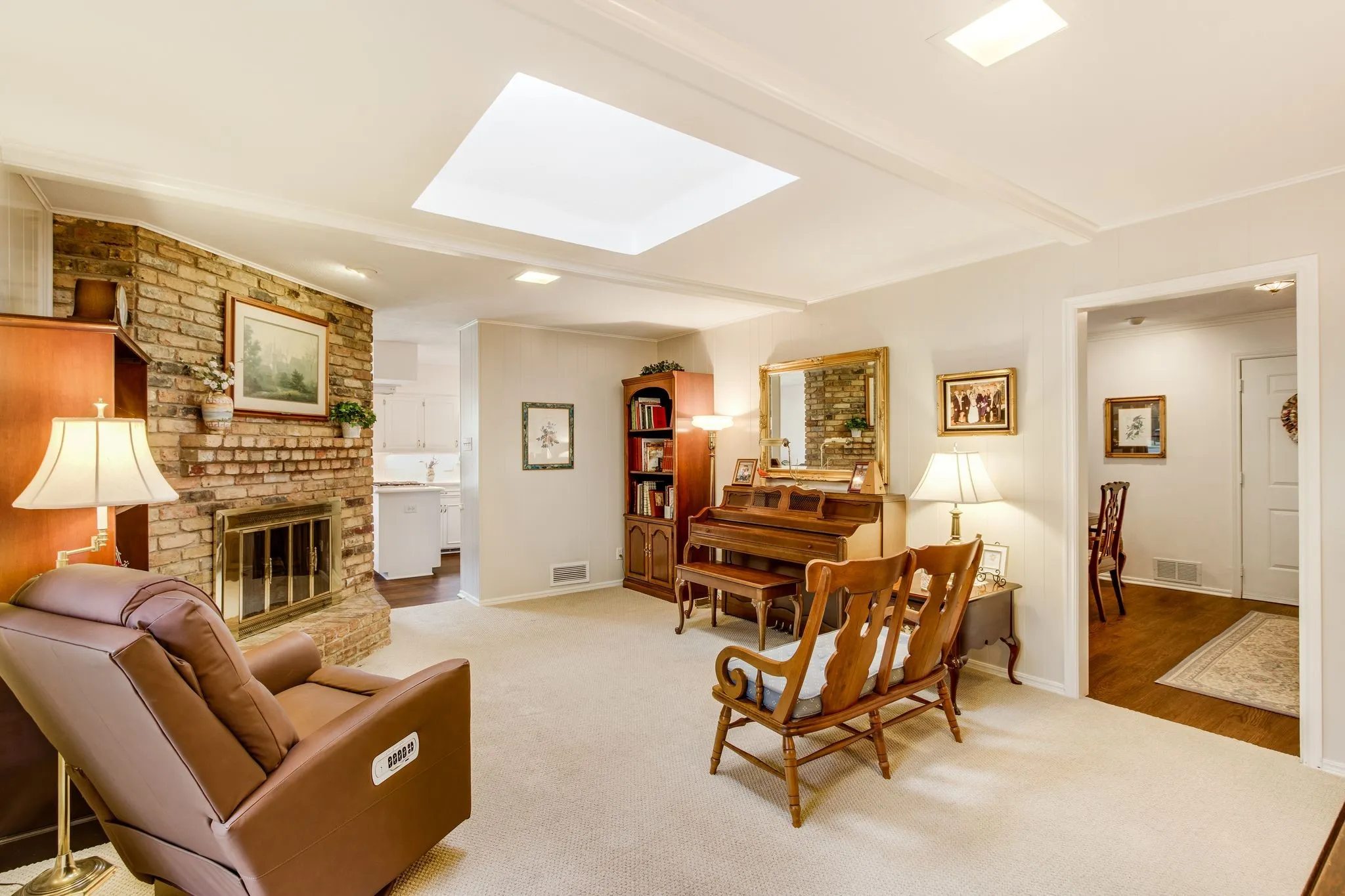 Spacious living area featuring a brick fireplace, recessed lighting, crown molding, and a skylight