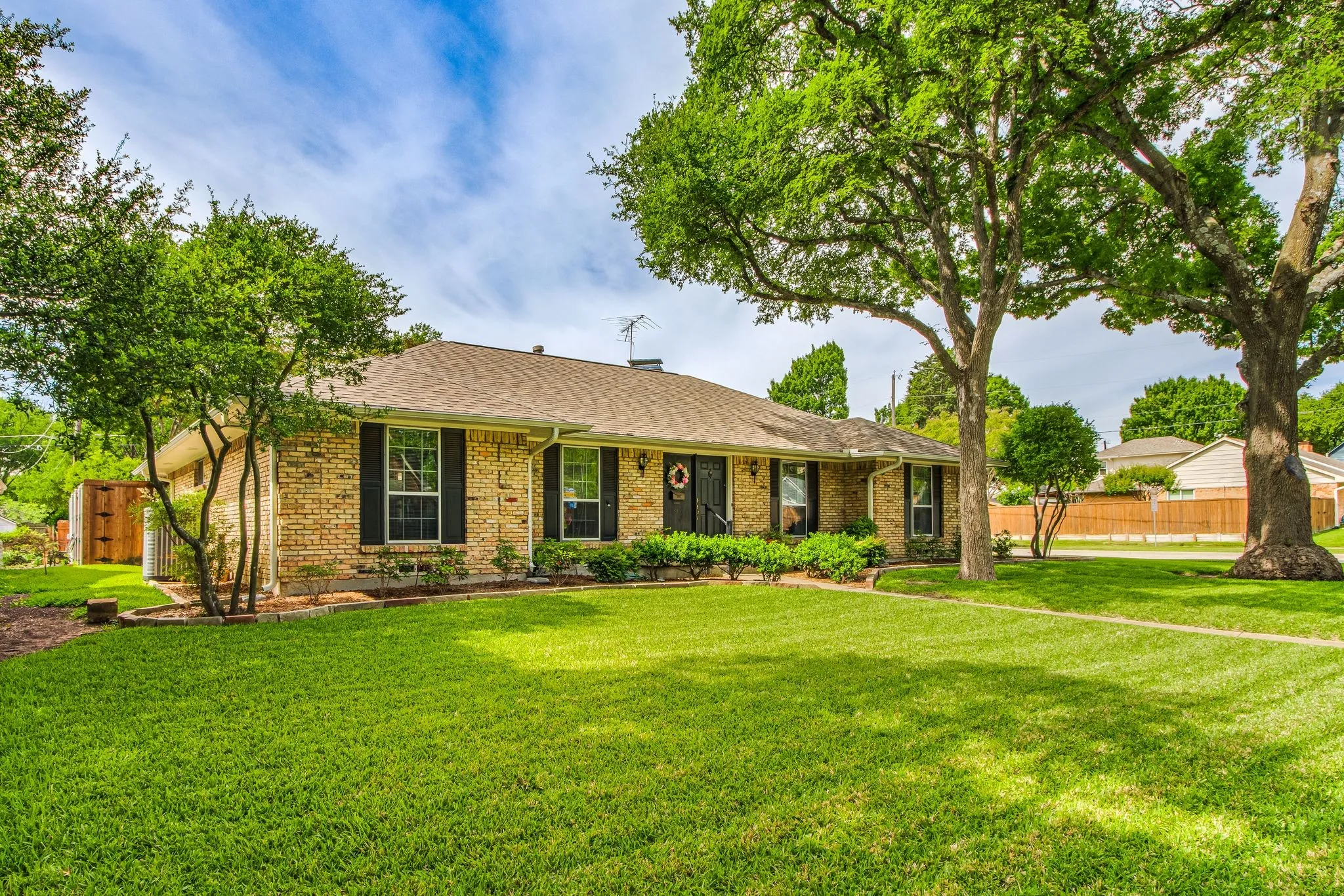 Brick exterior with a shingle roof and dark shutters