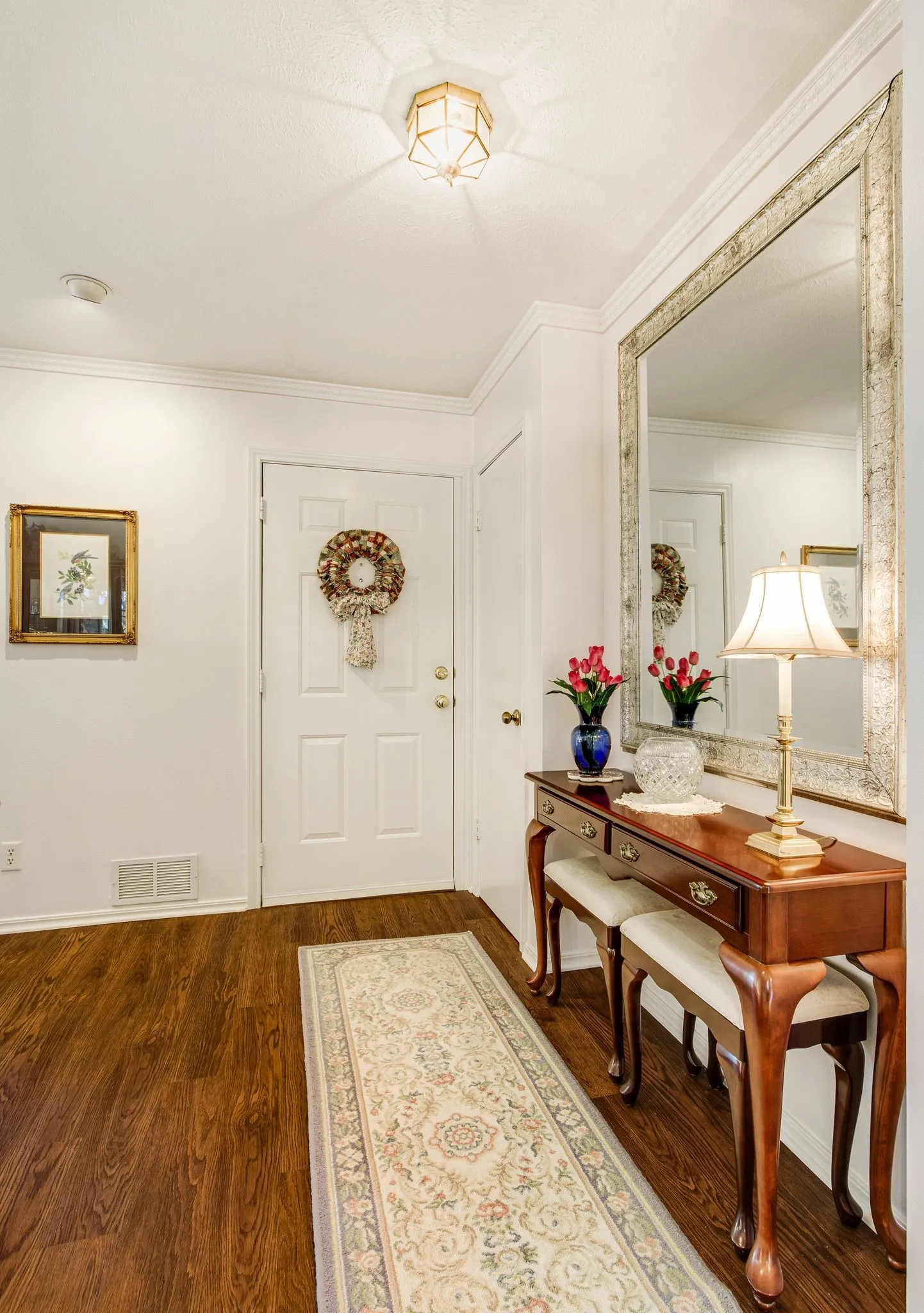 Entryway featuring wood-finish flooring, white paneled door with brass hardware, and a decorative ceiling light fixture