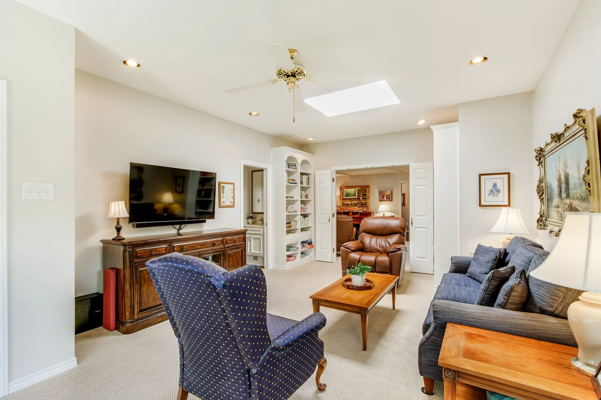 Recessed lighting and a central skylight illuminate this carpeted room