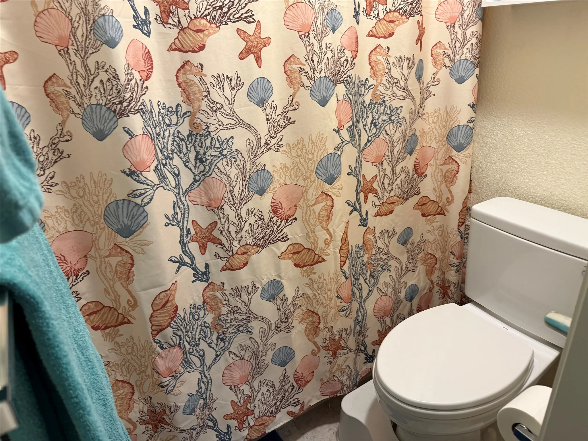 White toilet with closed lid, set against a textured light-colored wall