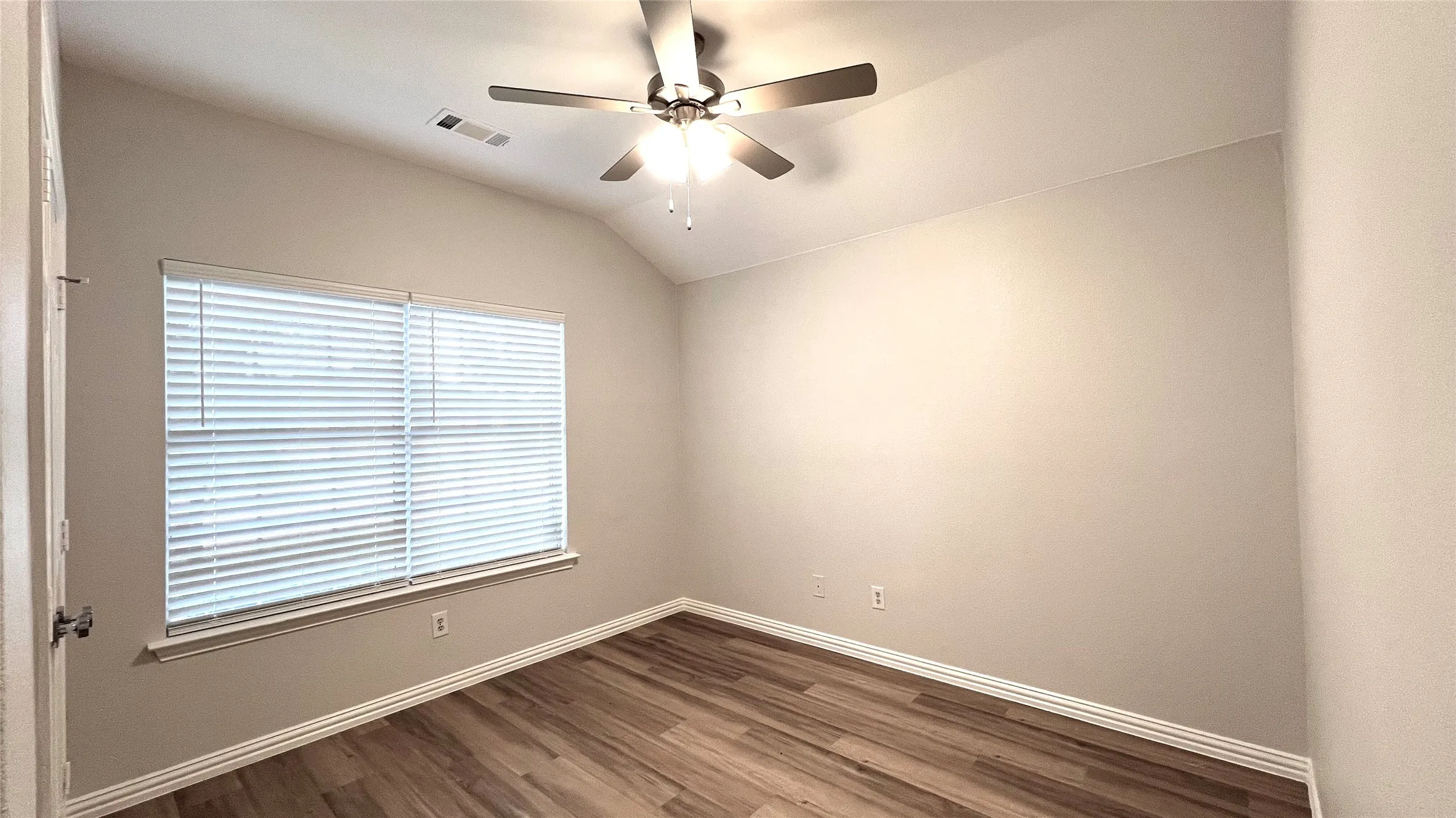 Room featuring wood-finish flooring, a window with blinds, a ceiling fan, and vaulted ceilings