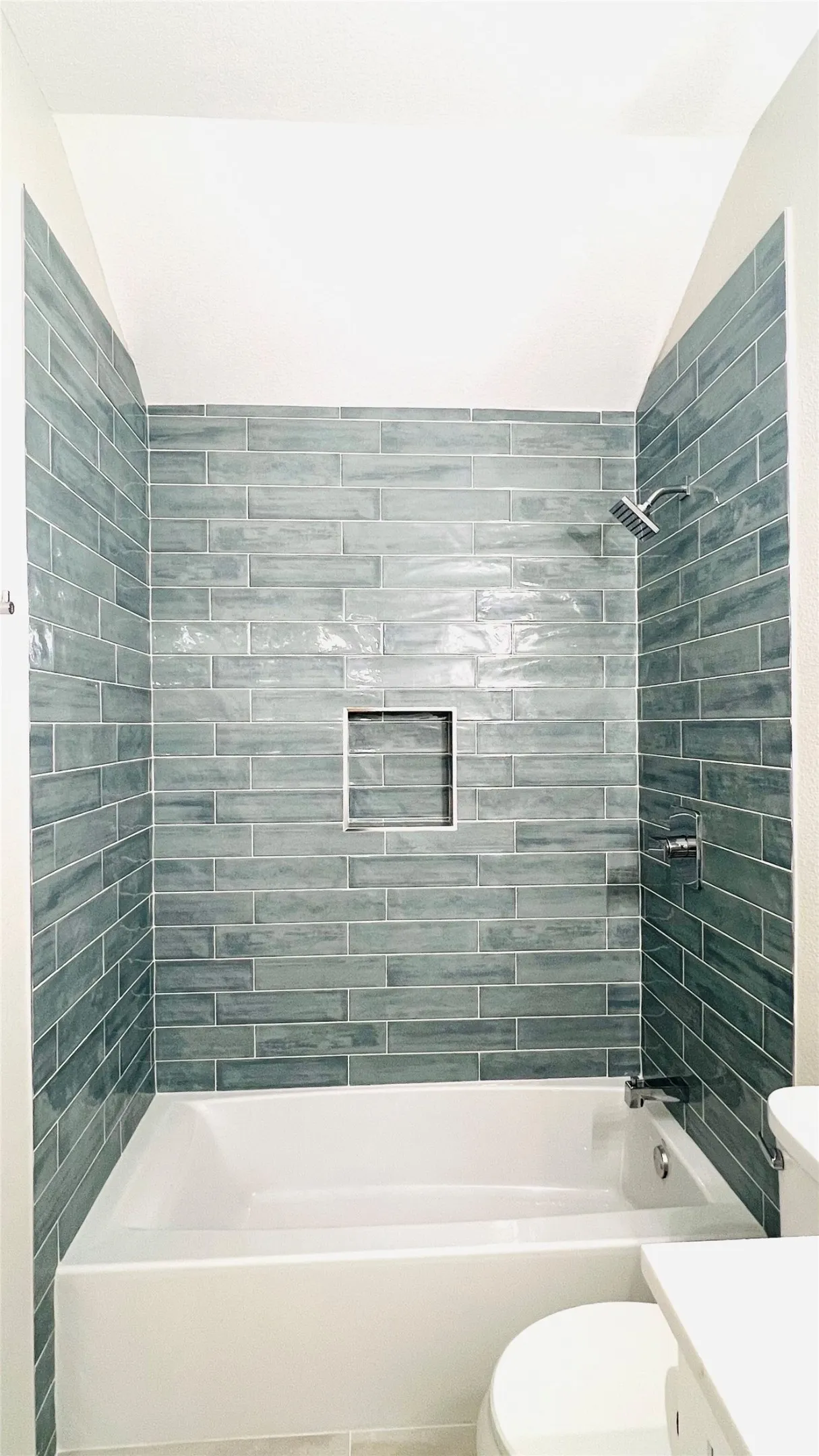 Bathtub and shower combination featuring subway tile surround in a stacked pattern with a recessed niche