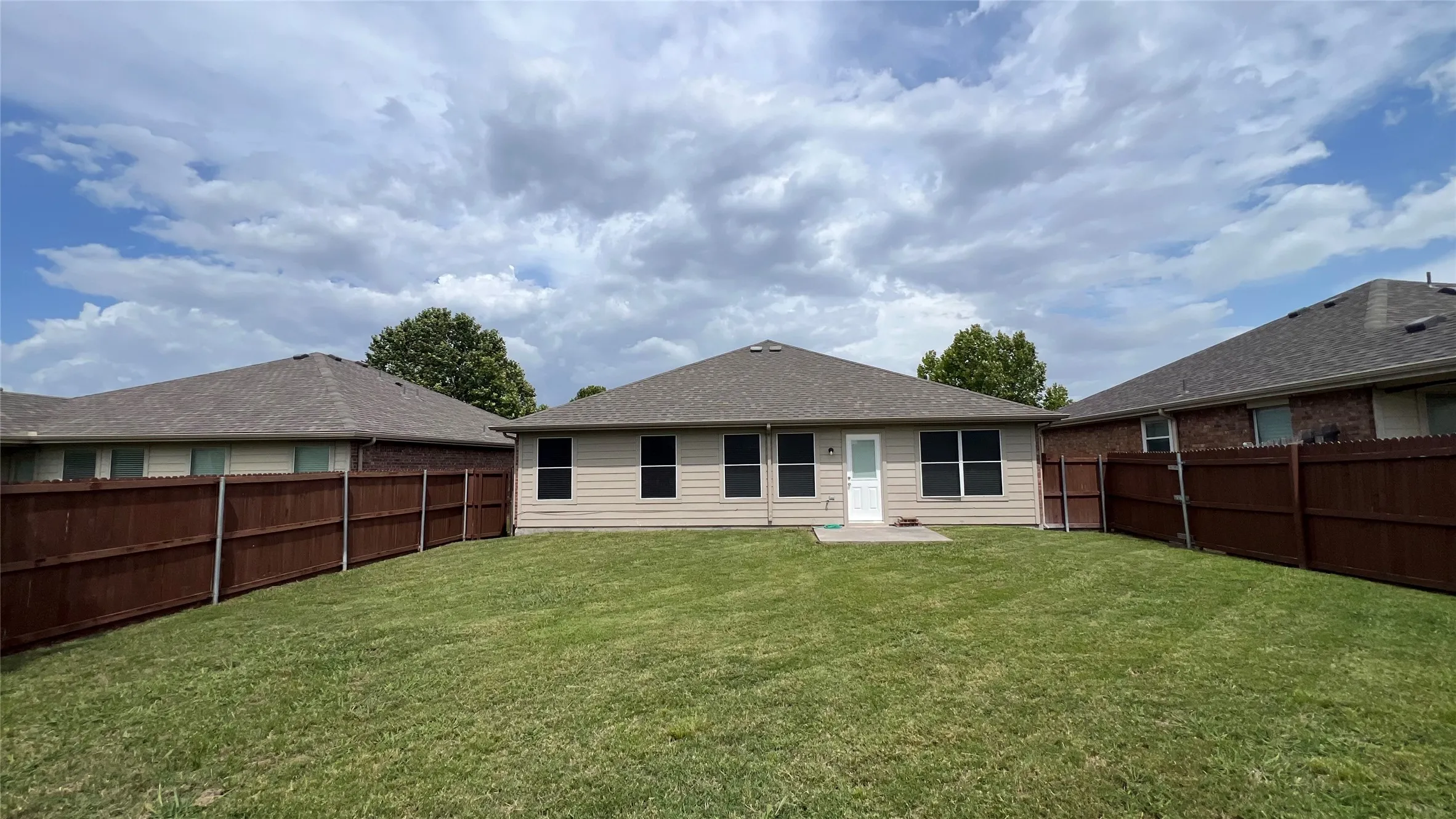Expansive green lawn with a full privacy fence