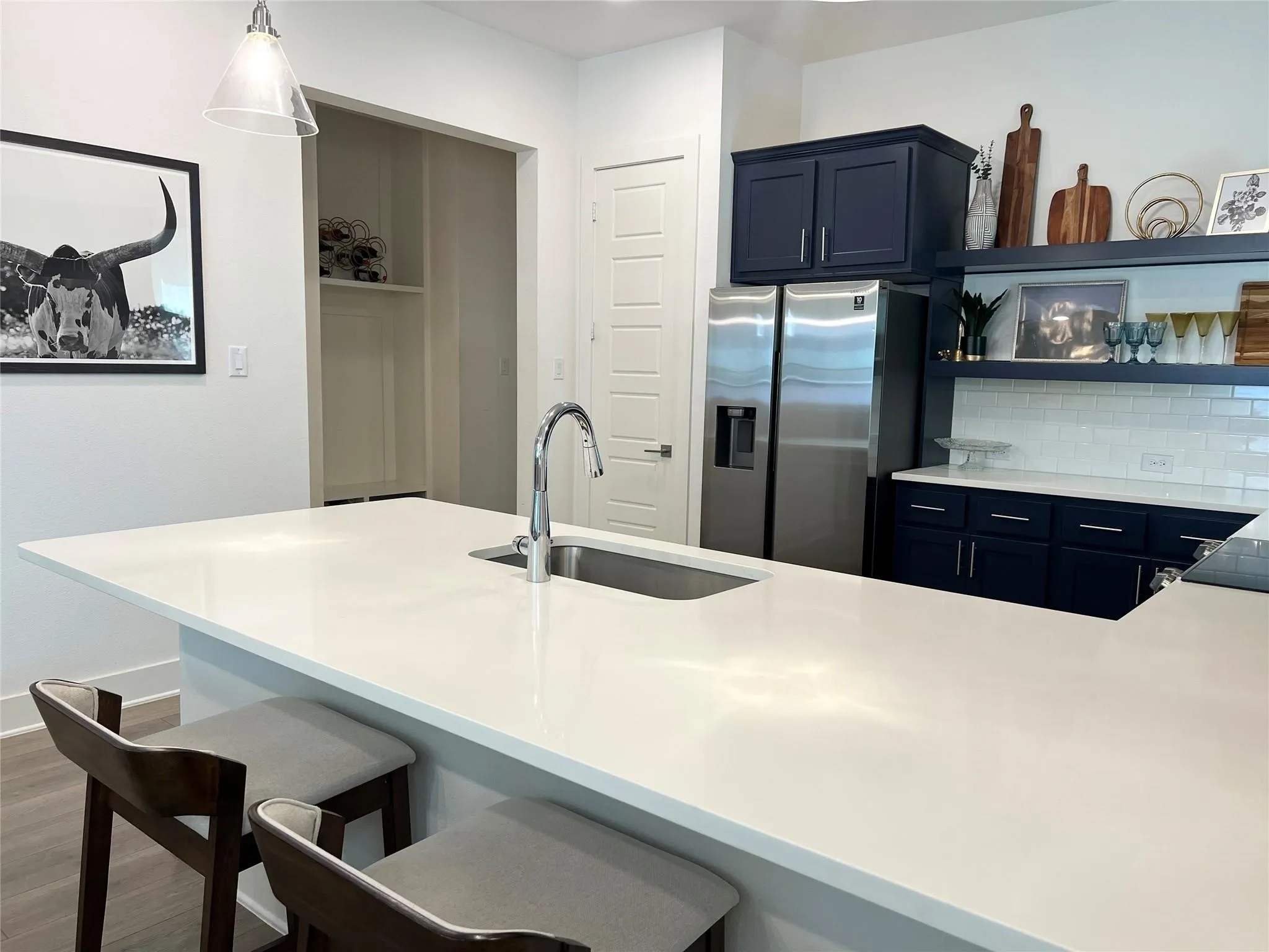 Alternate view of kitcken with view of stainless steel fridge, and entry way to powder bath and two car garage