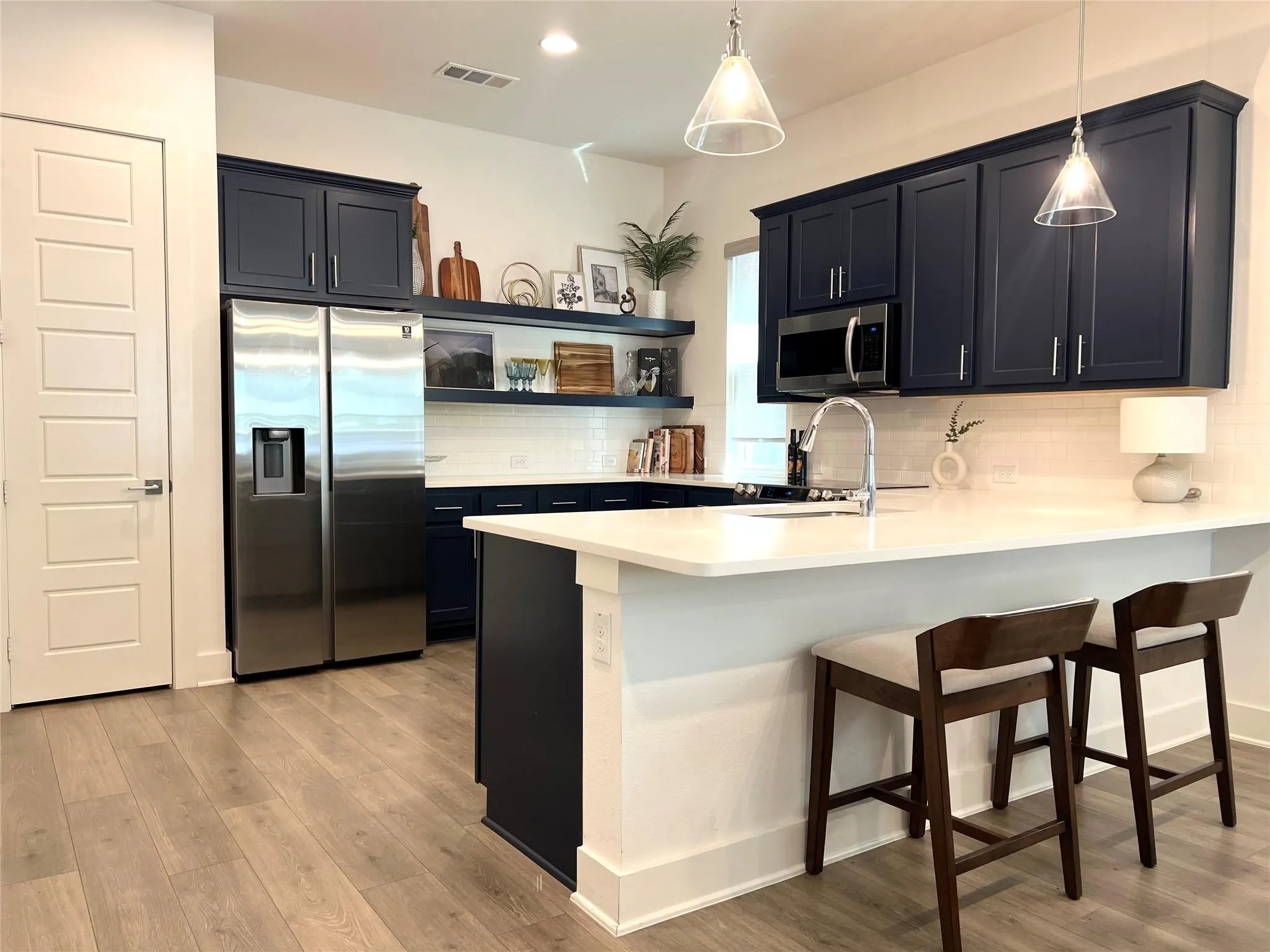 Kitchen with hanging light fixtures, and kitchen peninsula with bar seating