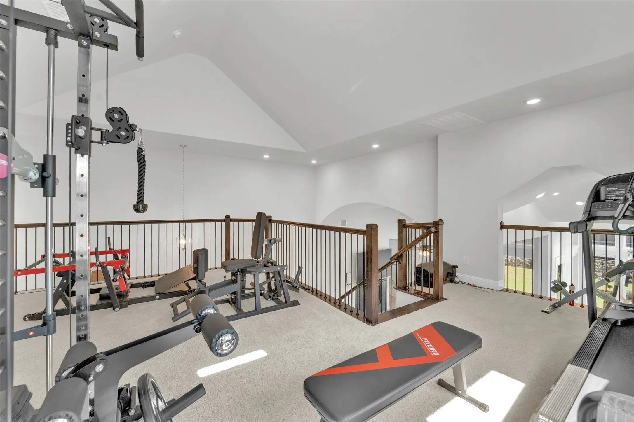Spacious loft area featuring vaulted ceilings, recessed lighting, and soft carpet flooring