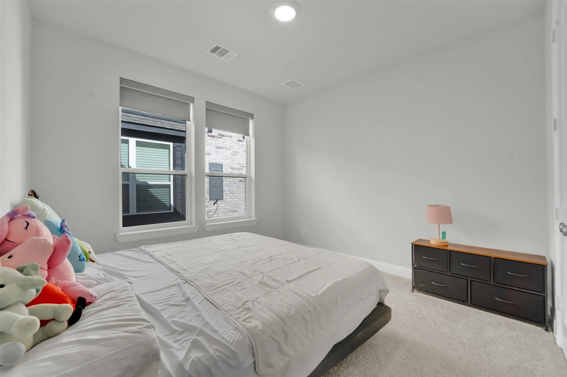 Bright bedroom featuring light gray walls and plush carpeting