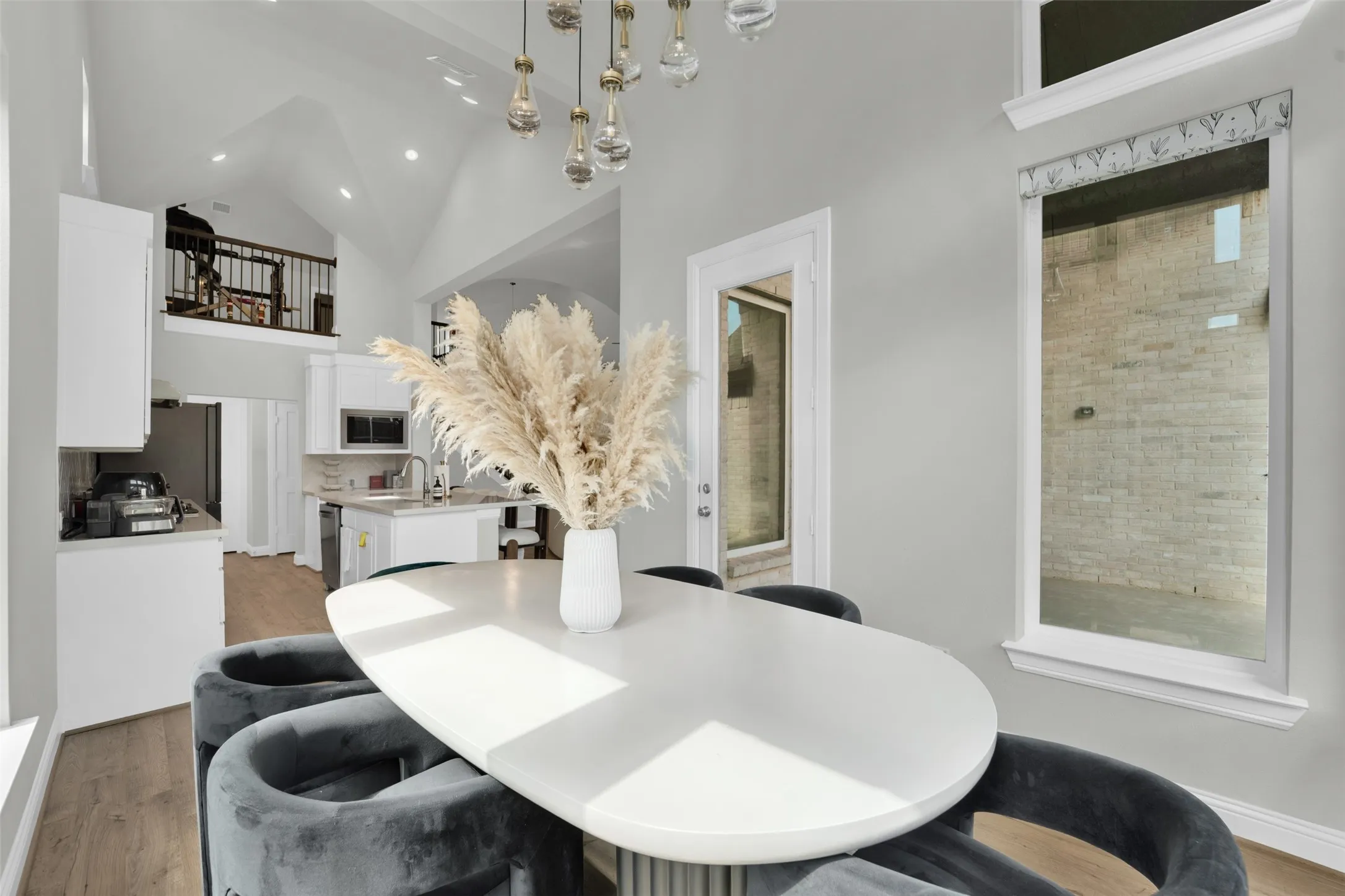 Spacious dining area featuring a modern oval table, contemporary light fixture, and wood-finish flooring