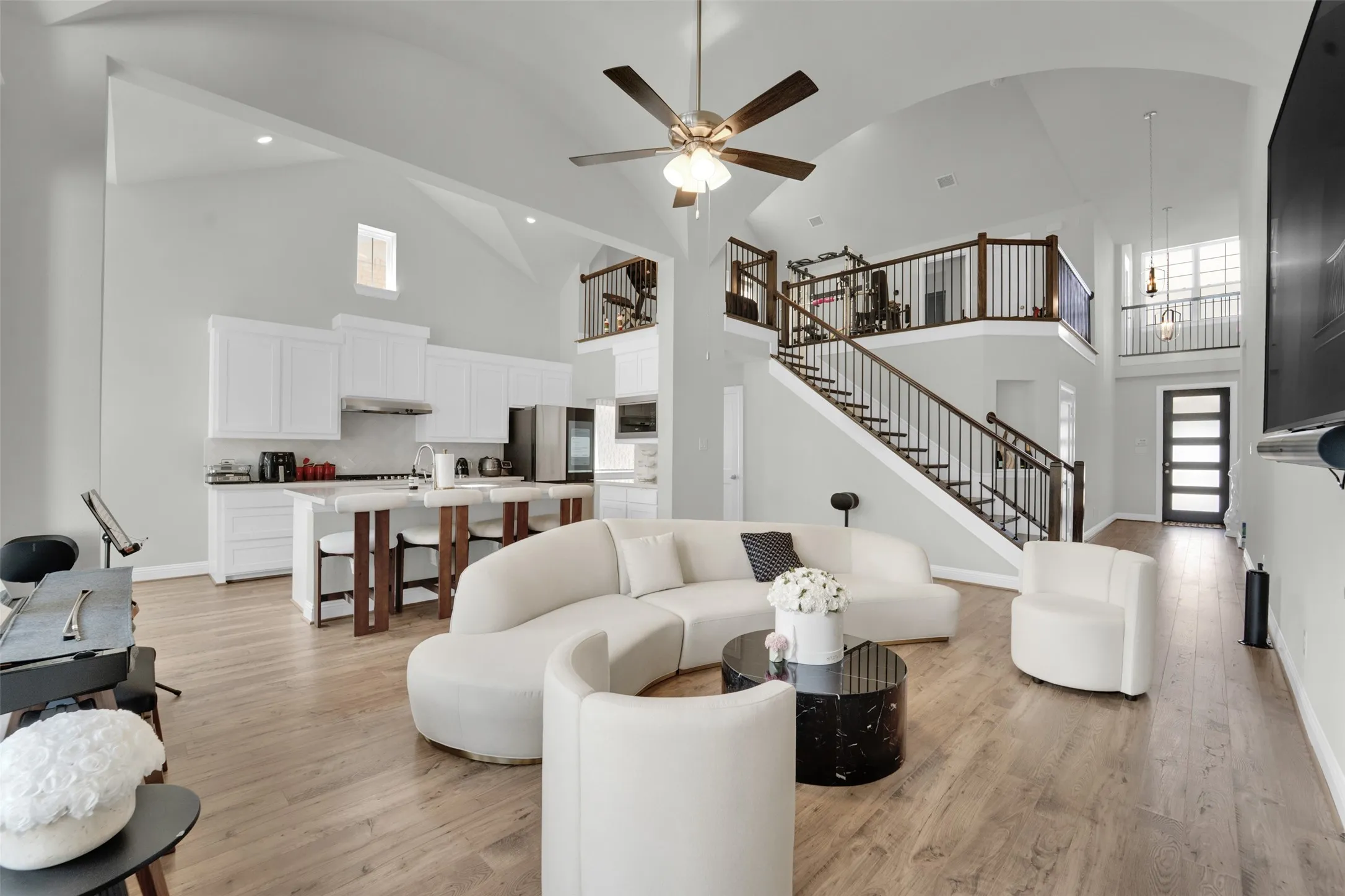 Expansive open-concept living area featuring high vaulted ceilings, light wood-finish flooring, a contemporary ceiling fan, and recessed lighting