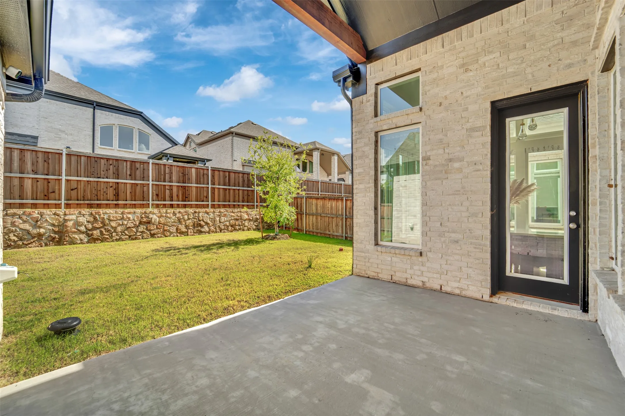 Covered patio featuring a concrete slab and a light brick exterior