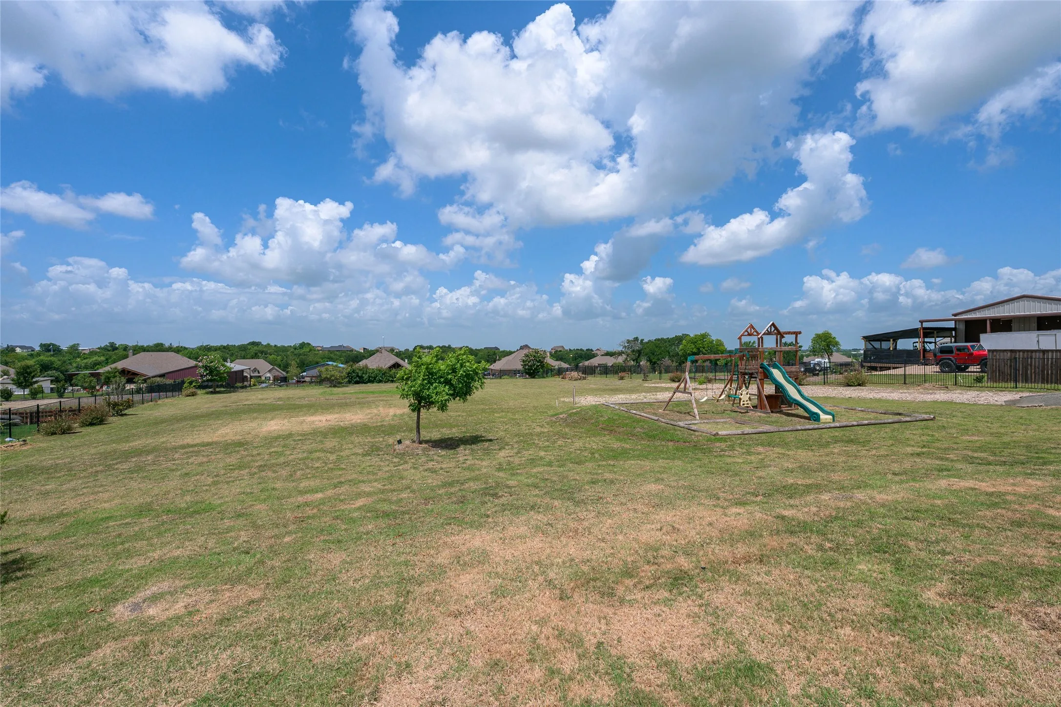Expansive grassy area featuring a children's play structure with slides and swings