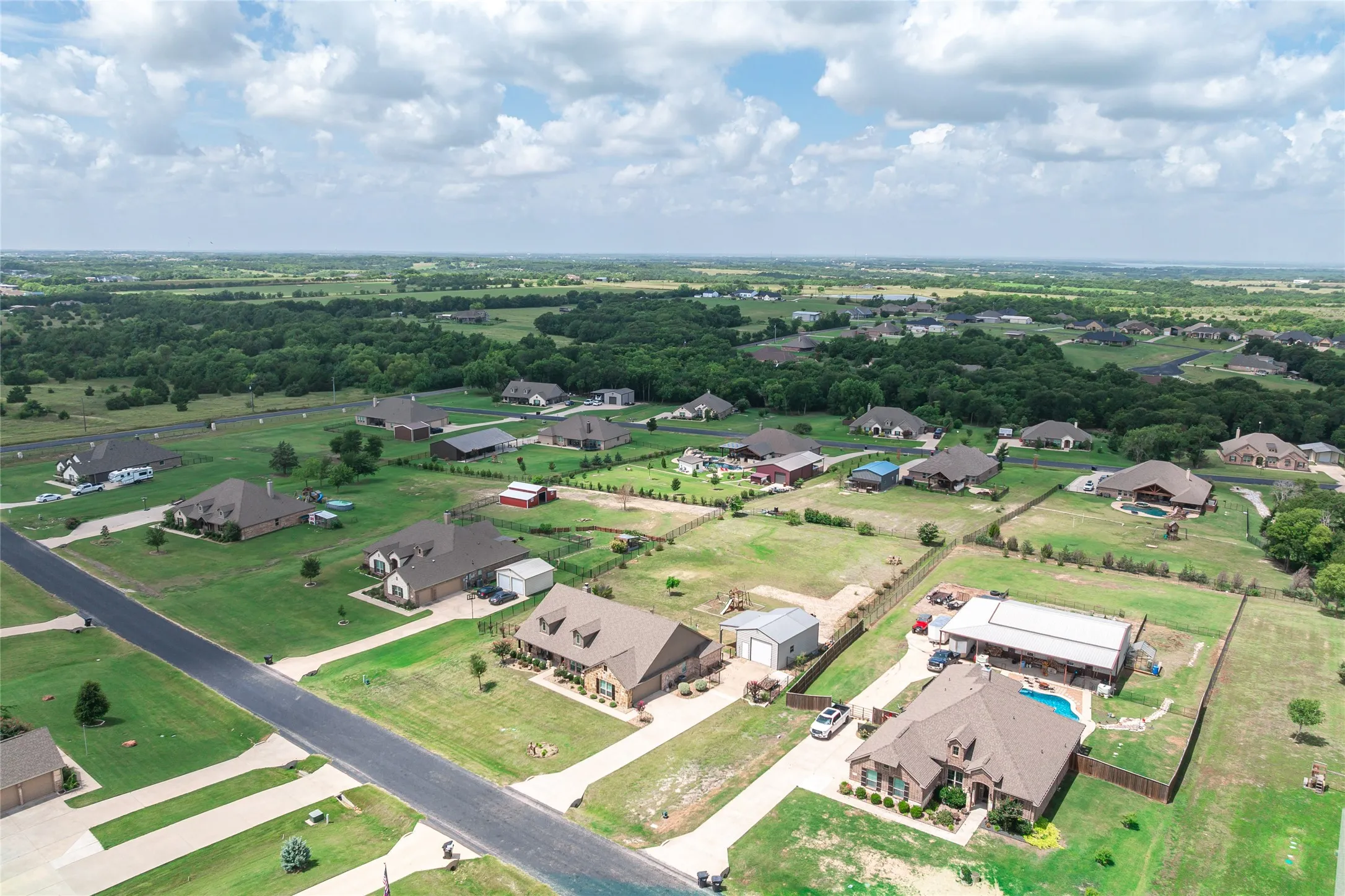 Expansive rural neighborhood featuring single-story homes with ample green space and mature tree lines