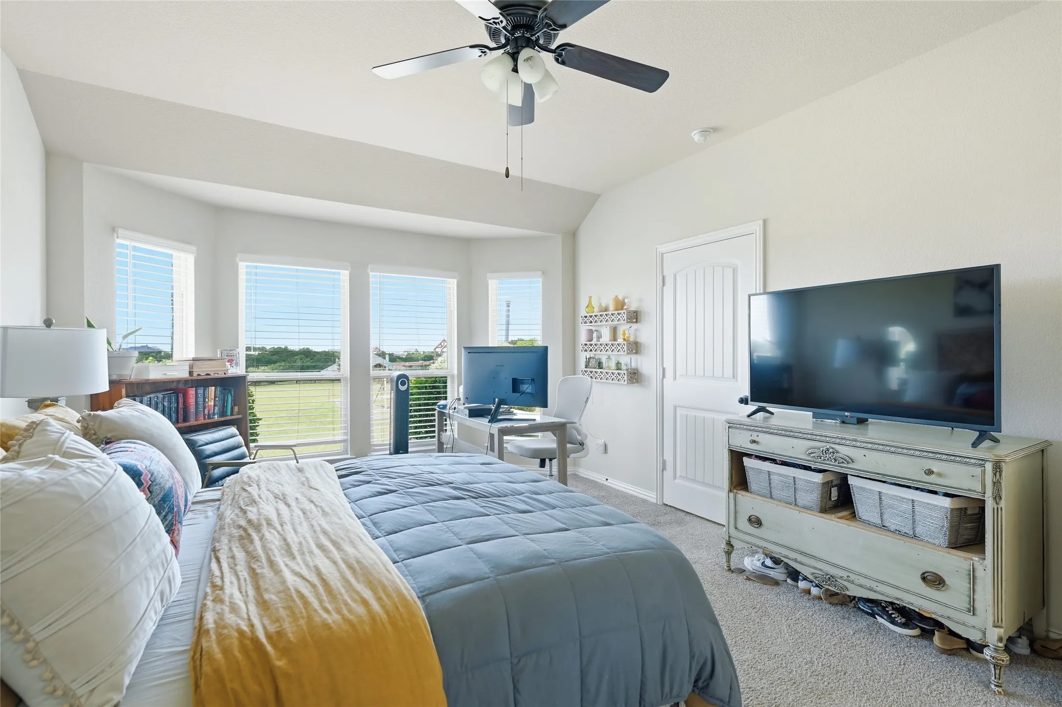 Bedroom featuring a bay window, ceiling fan, vaulted ceiling, and carpet flooring