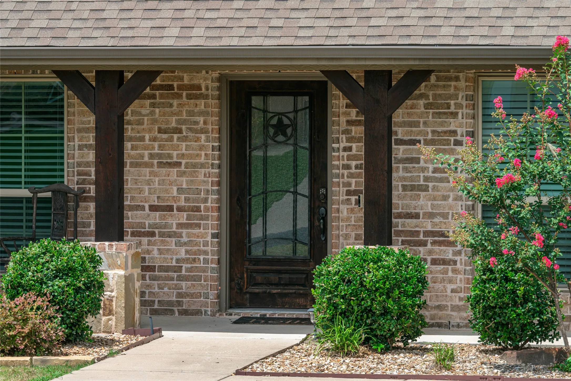 Brick facade with a dark wood-finish entry door featuring decorative glass and a star emblem