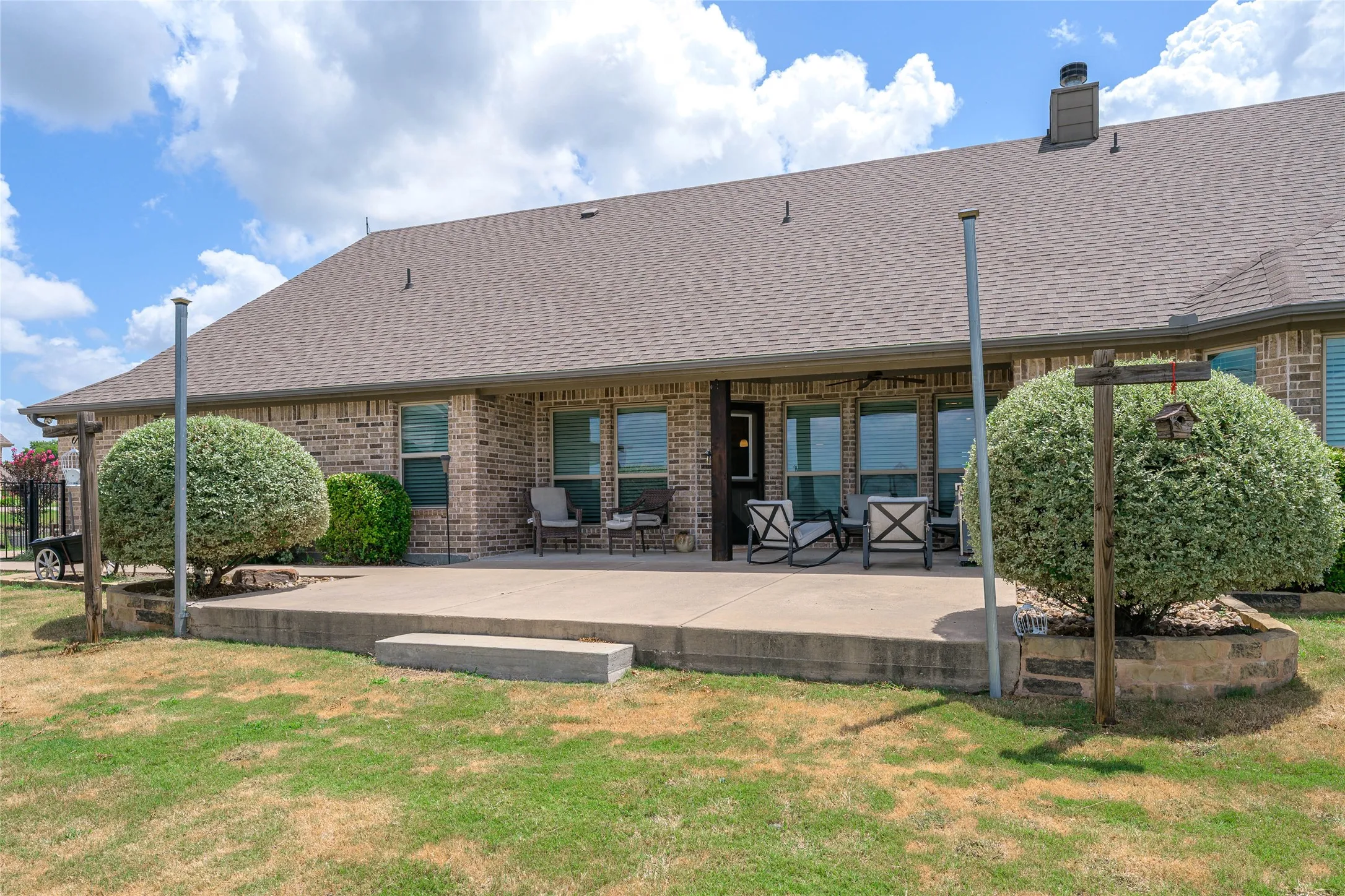 Expansive rear patio area featuring a concrete surface and a partial overhang