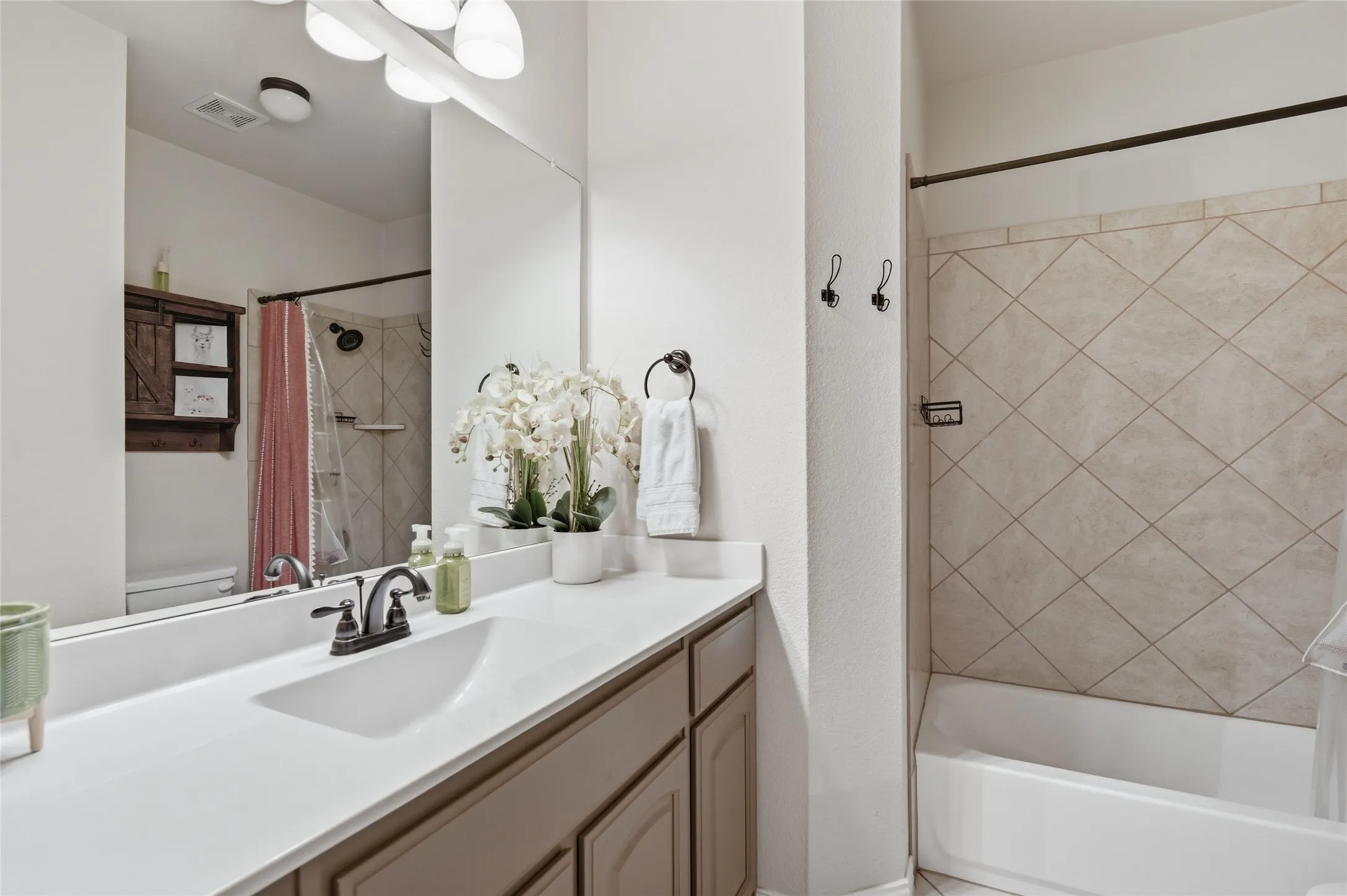 Bathroom featuring a single vanity with a white countertop, an undermount sink, and dark-finished faucet