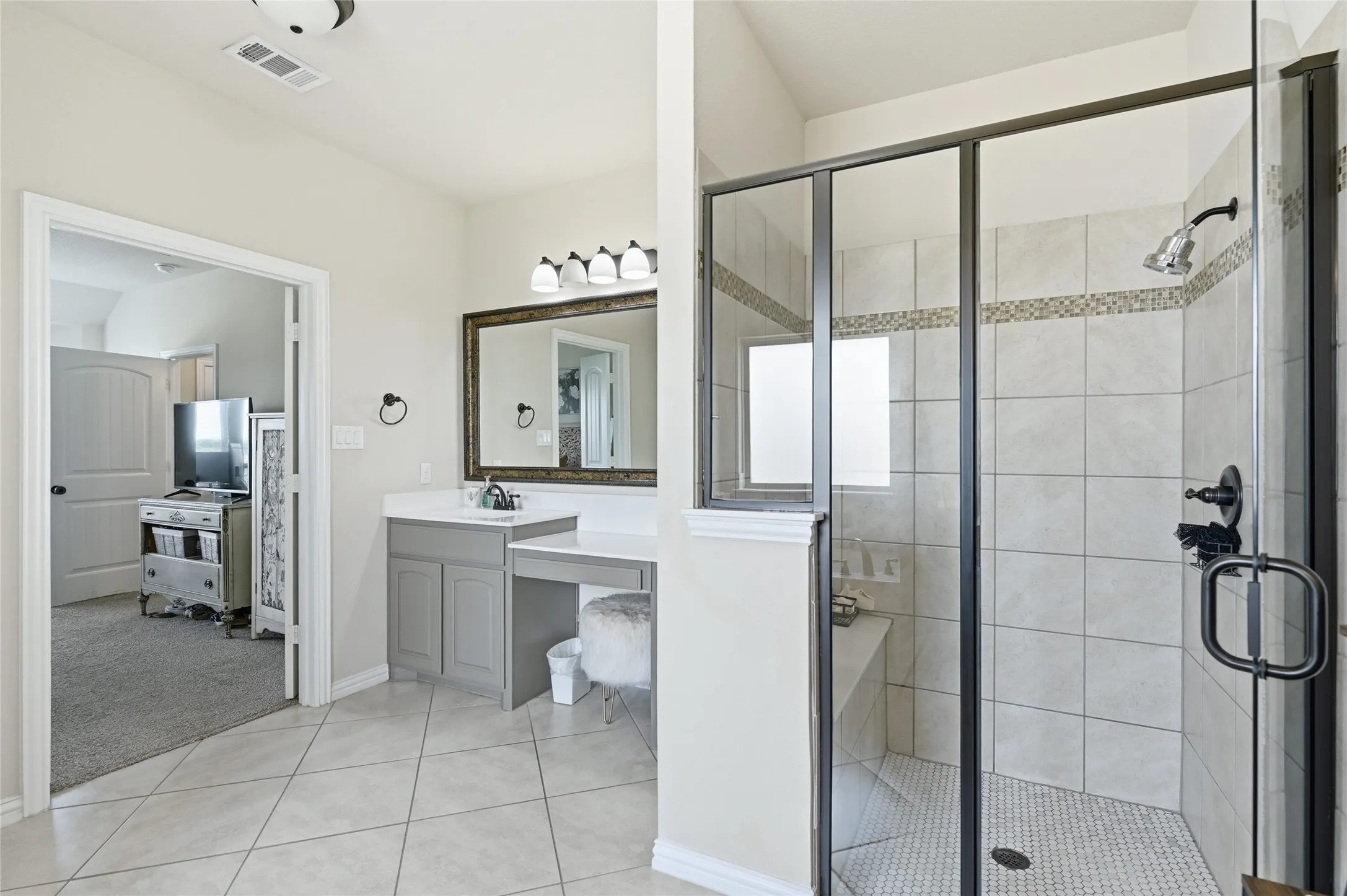 Spacious bathroom featuring a glass-enclosed shower with tiled walls and a mosaic accent strip