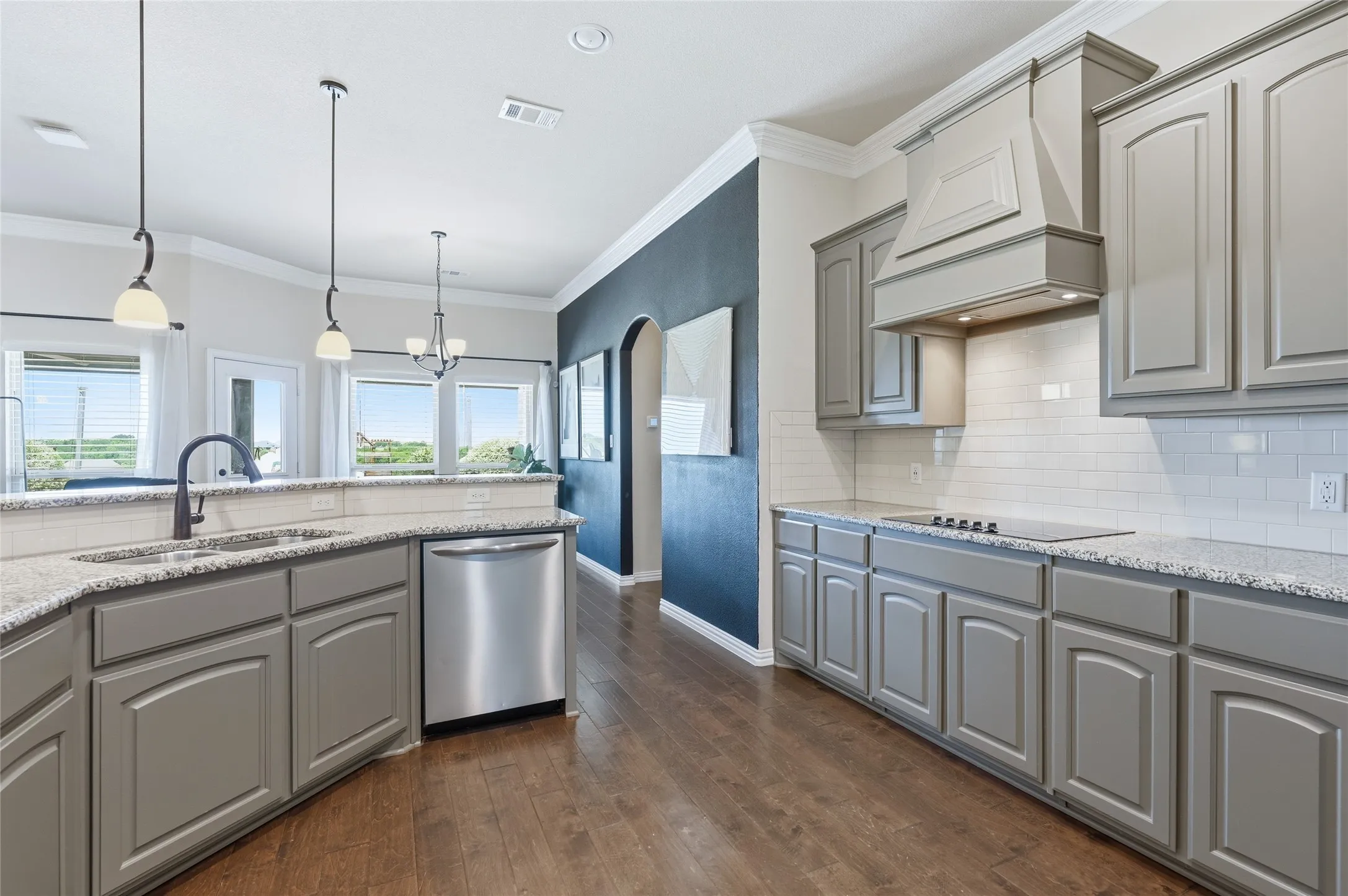 Kitchen featuring gray cabinetry, light speckled countertops, a stainless steel dishwasher, and wood-finish flooring