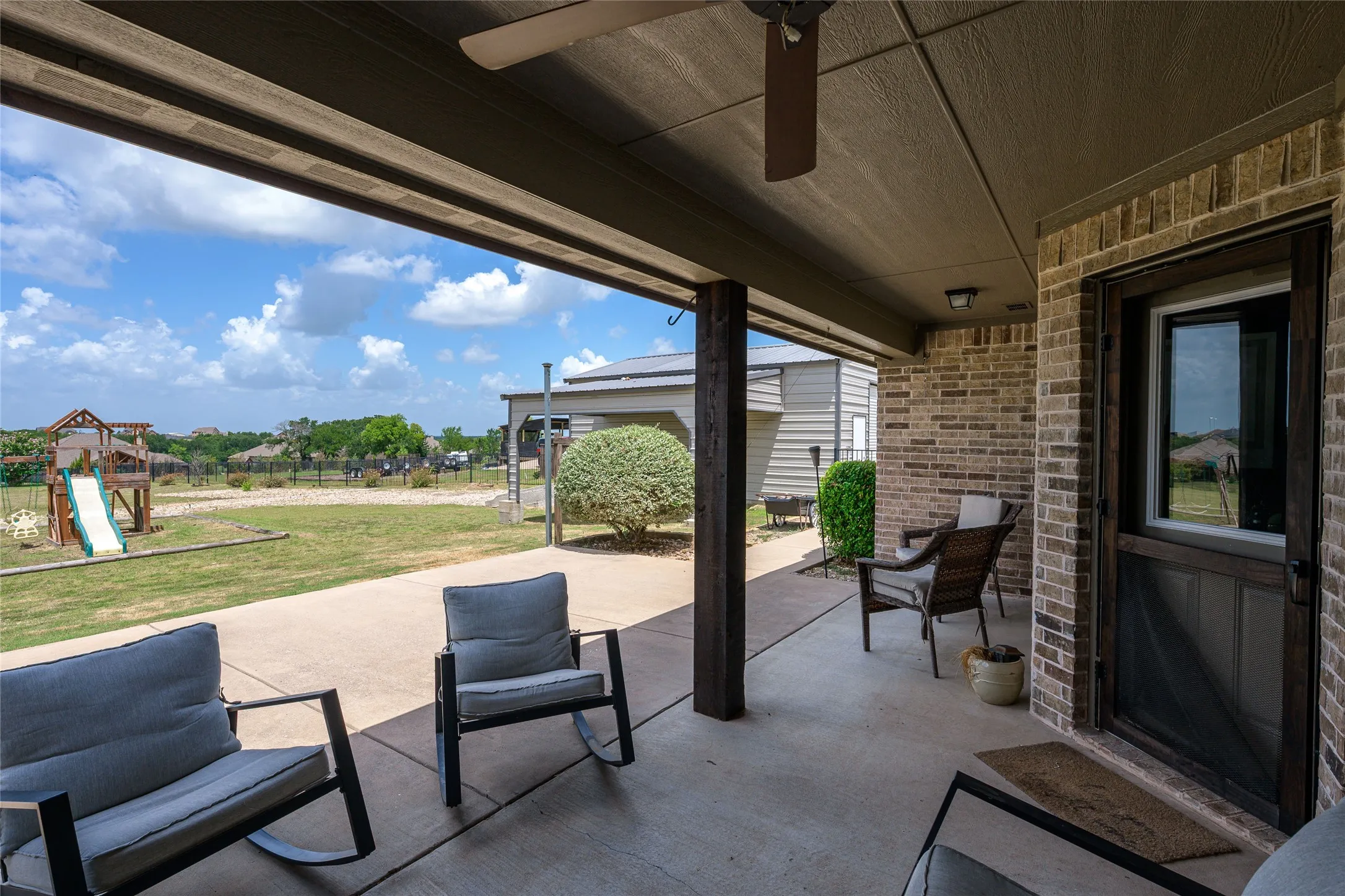 Covered patio featuring concrete flooring and a brick exterior wall