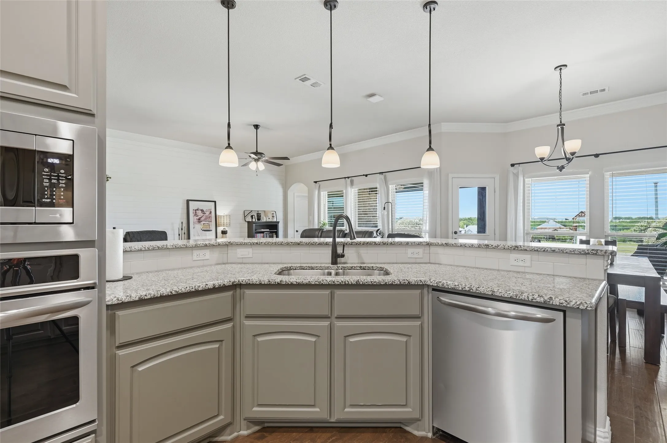 Kitchen featuring gray cabinetry, stainless steel appliances, speckled countertops, and a subway tile backsplash