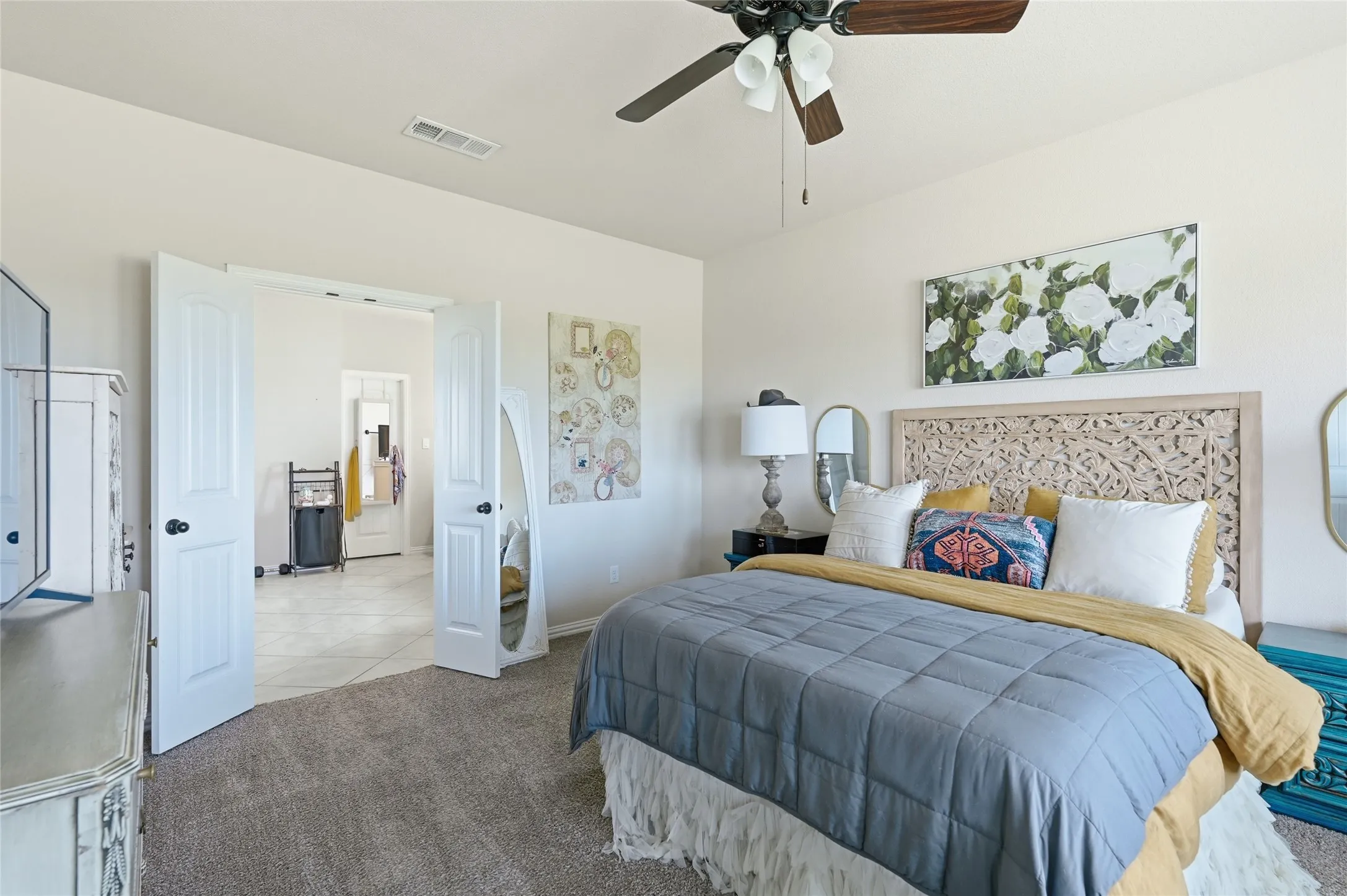 Bedroom featuring a carved wood headboard, a ceiling fan with integrated lighting, and carpet flooring