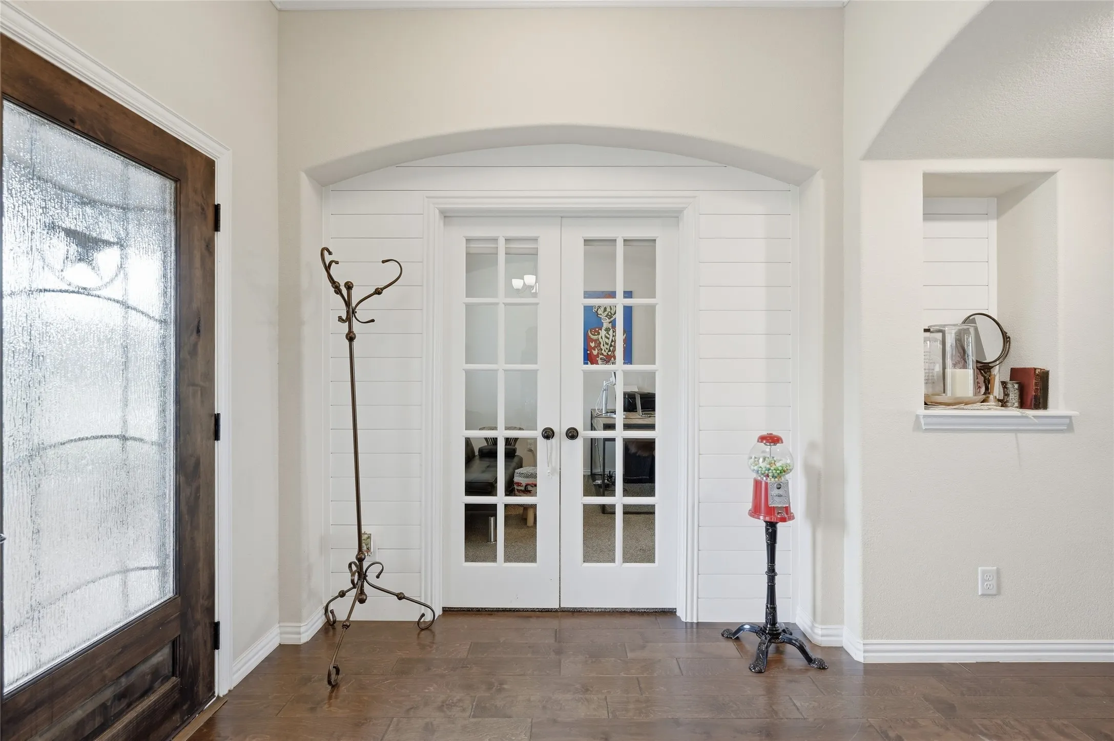 Entryway featuring wood-finish flooring, a dark wood-finish door with decorative glass, and white French doors