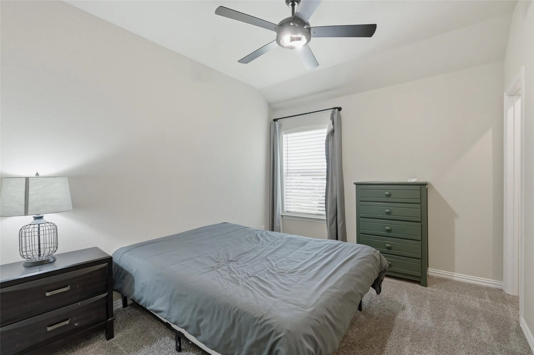 Carpeted room featuring a ceiling fan with integrated lighting, a window with blinds and drapes, and neutral wall paint