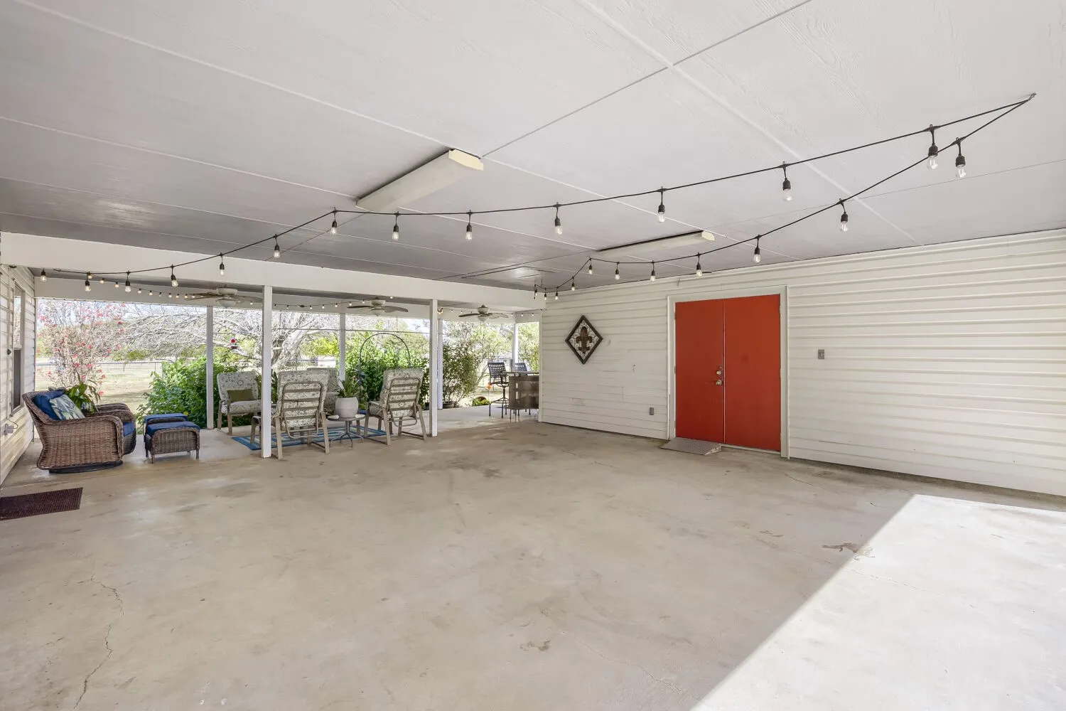 Expansive covered patio with a concrete surface, white siding, and double red doors