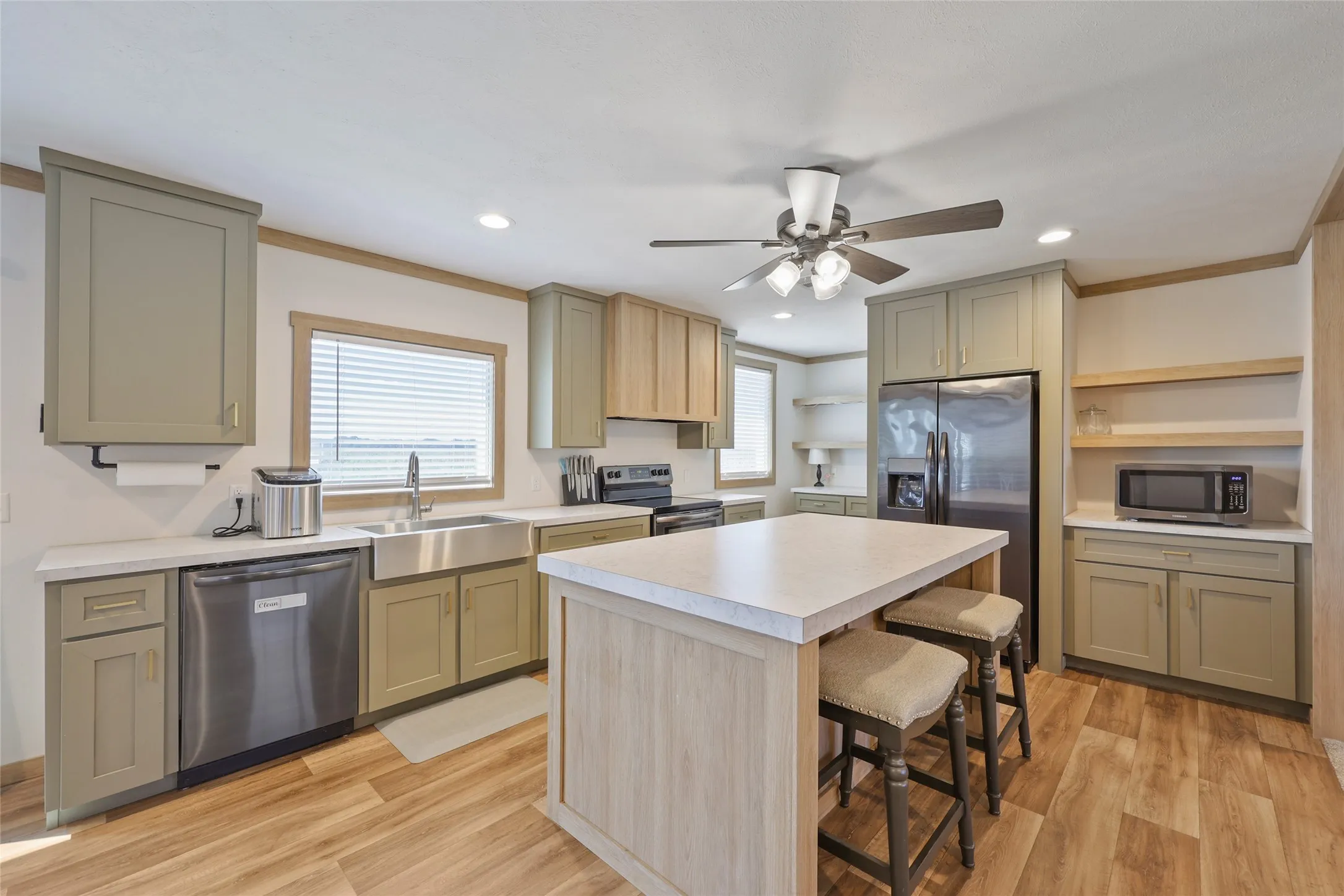 Spacious kitchen featuring an island with countertop seating, wood-finish flooring, recessed lighting, and stainless steel appliances