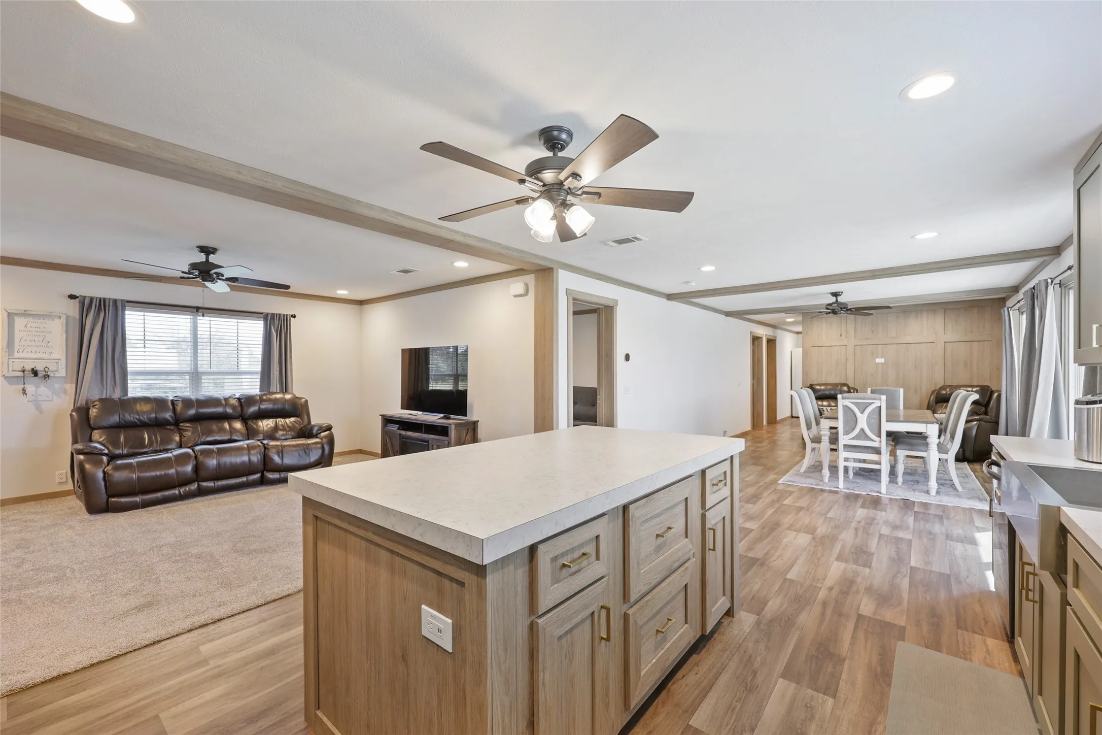 Spacious open-concept interior featuring light wood-finish flooring, recessed lighting, and ceiling fans