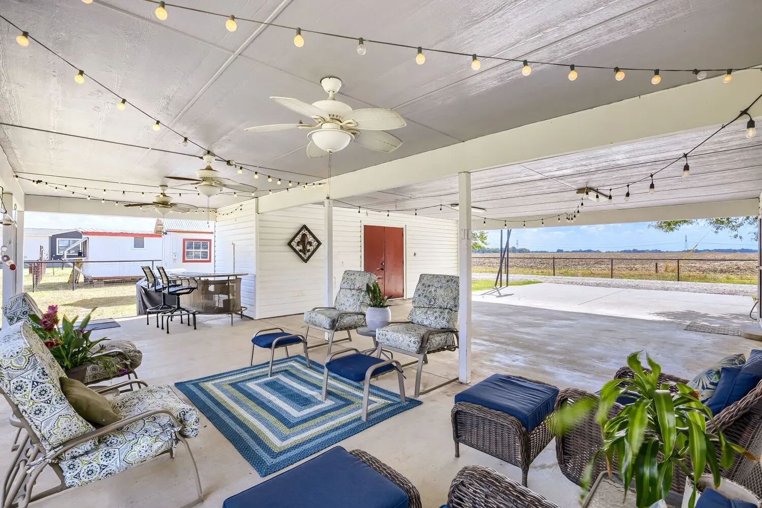 Expansive covered patio featuring a concrete surface, multiple ceiling fans, and string lighting