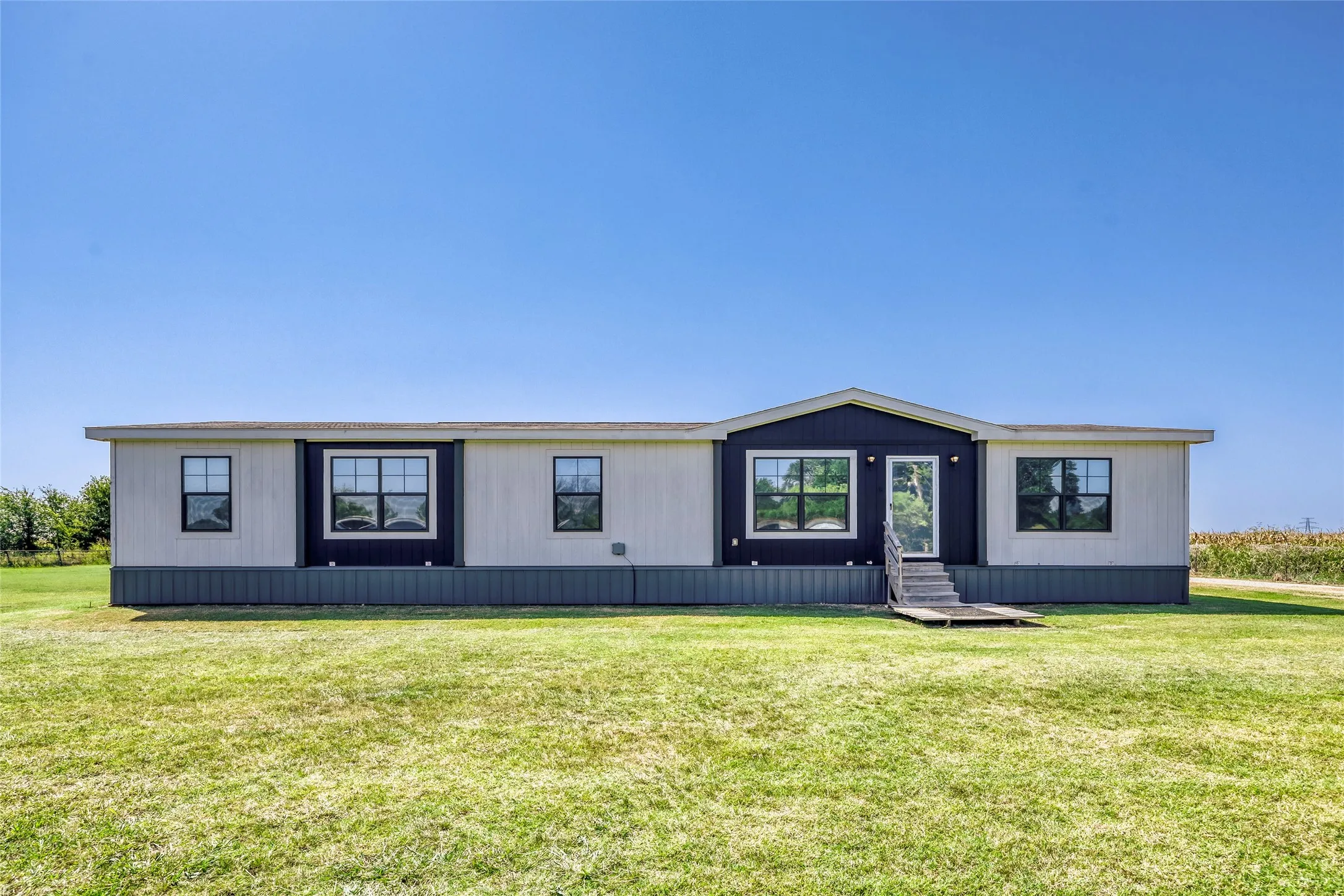 Single-story residence featuring light-colored siding with dark trim accents and multiple windows