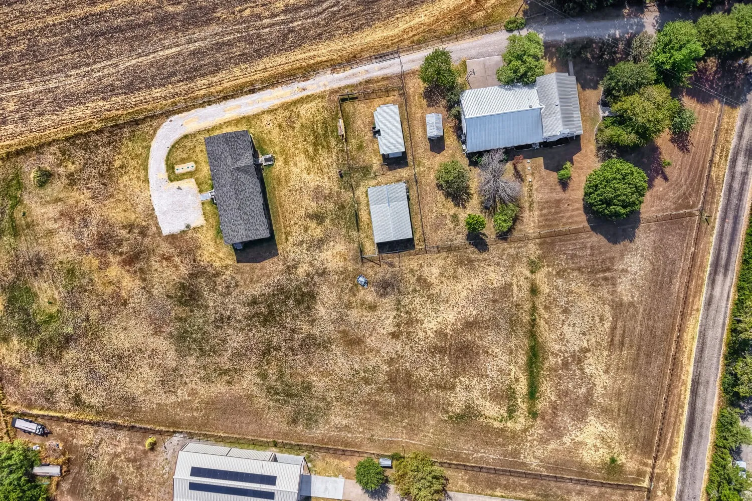 Expansive property featuring multiple structures, including a primary residence with a dark shingle roof and a separate structure with a metal roof