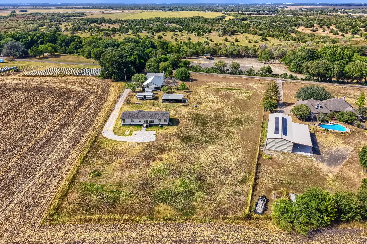 Expansive property featuring multiple structures, a swimming pool, and mature trees