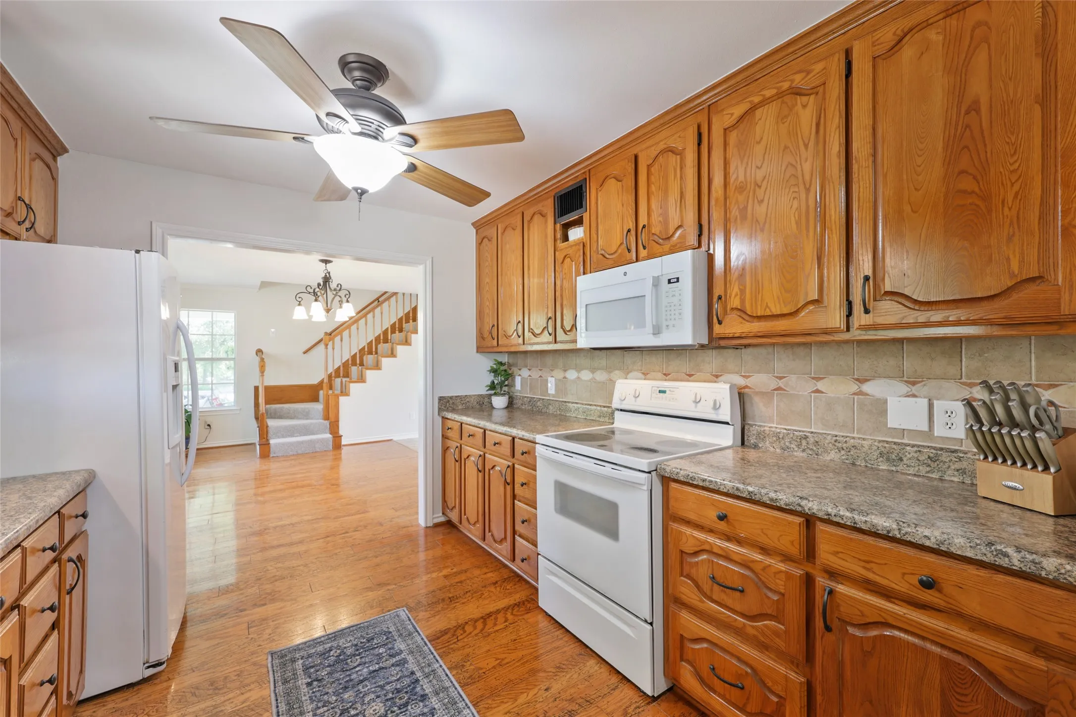 Kitchen featuring wood-finish cabinetry, speckled countertops, and a tiled backsplash