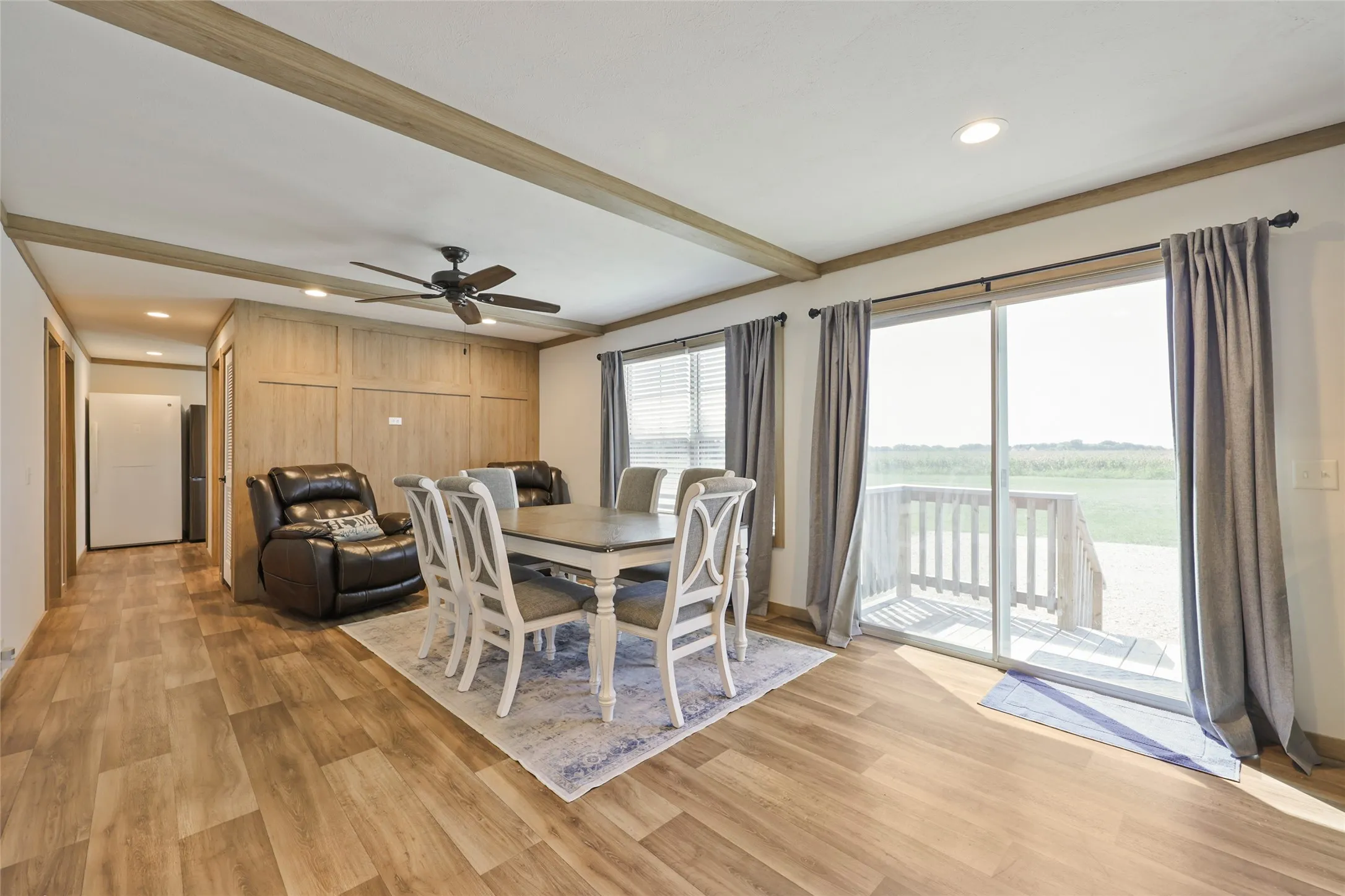 Open-concept living area with wood-finish flooring, ceiling beams, and recessed lighting