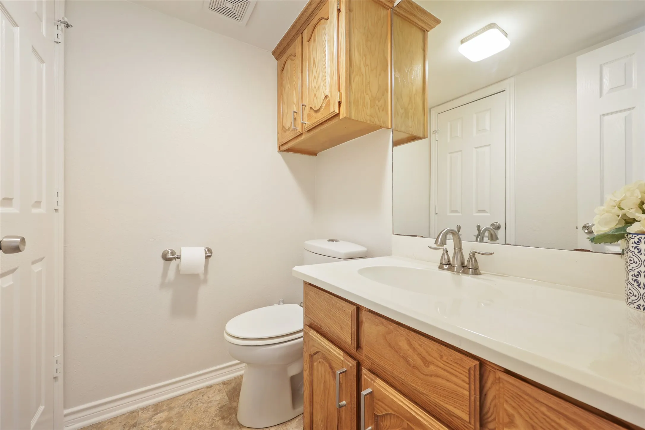 Bathroom featuring a vanity with wood cabinetry, a white countertop, and an integrated sink
