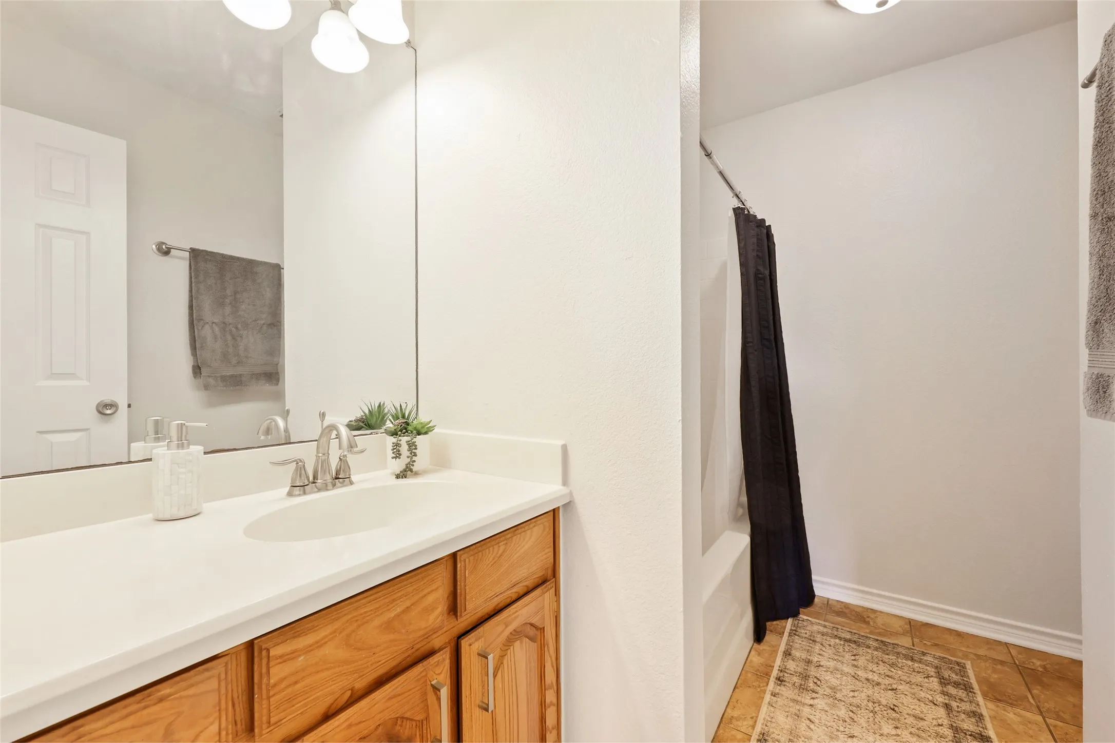  Bathroom featuring a wood-finish vanity with a white countertop, an oval undermount sink, and a chrome faucet