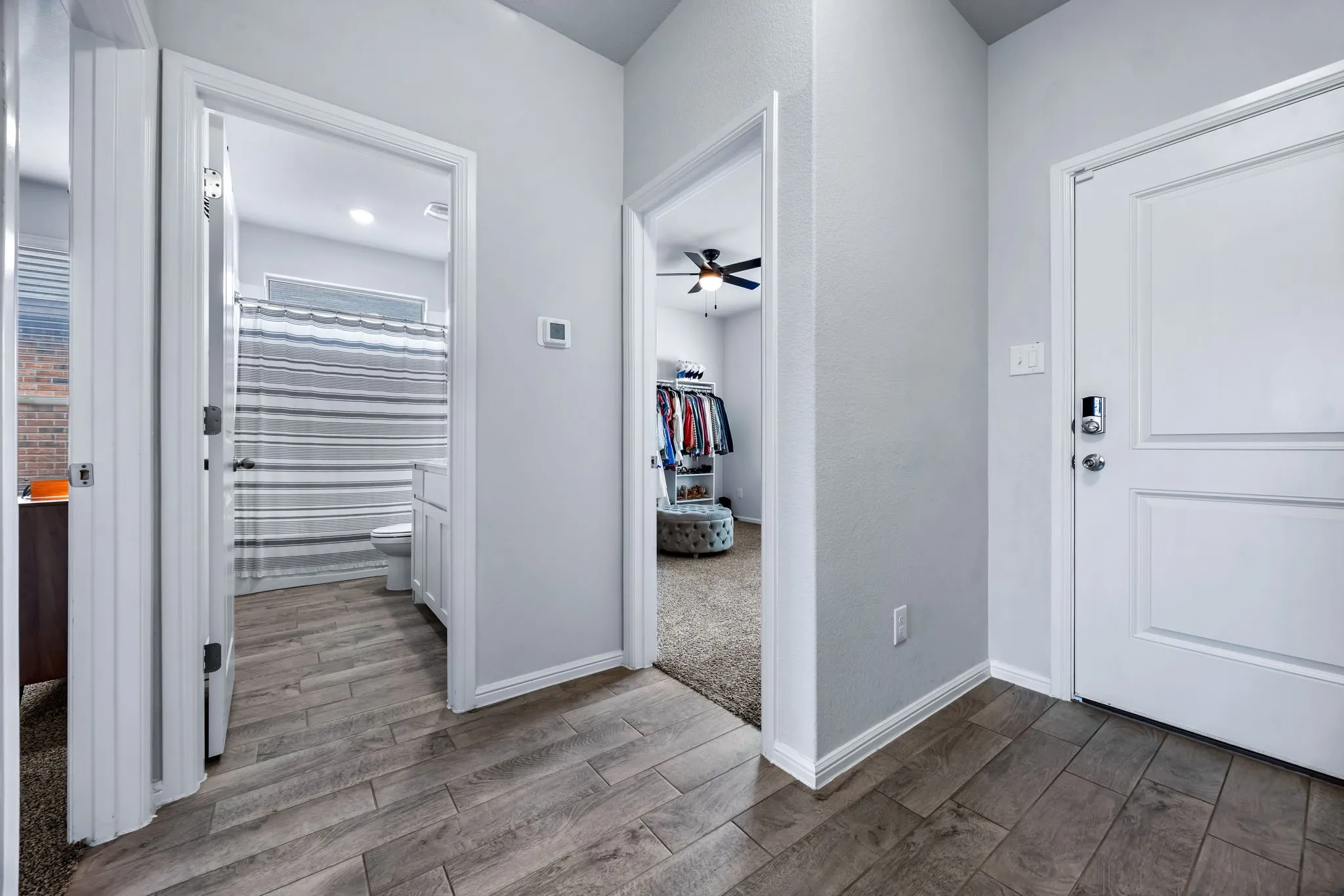 Hallway featuring wood-finish flooring, light grey walls, and white trim