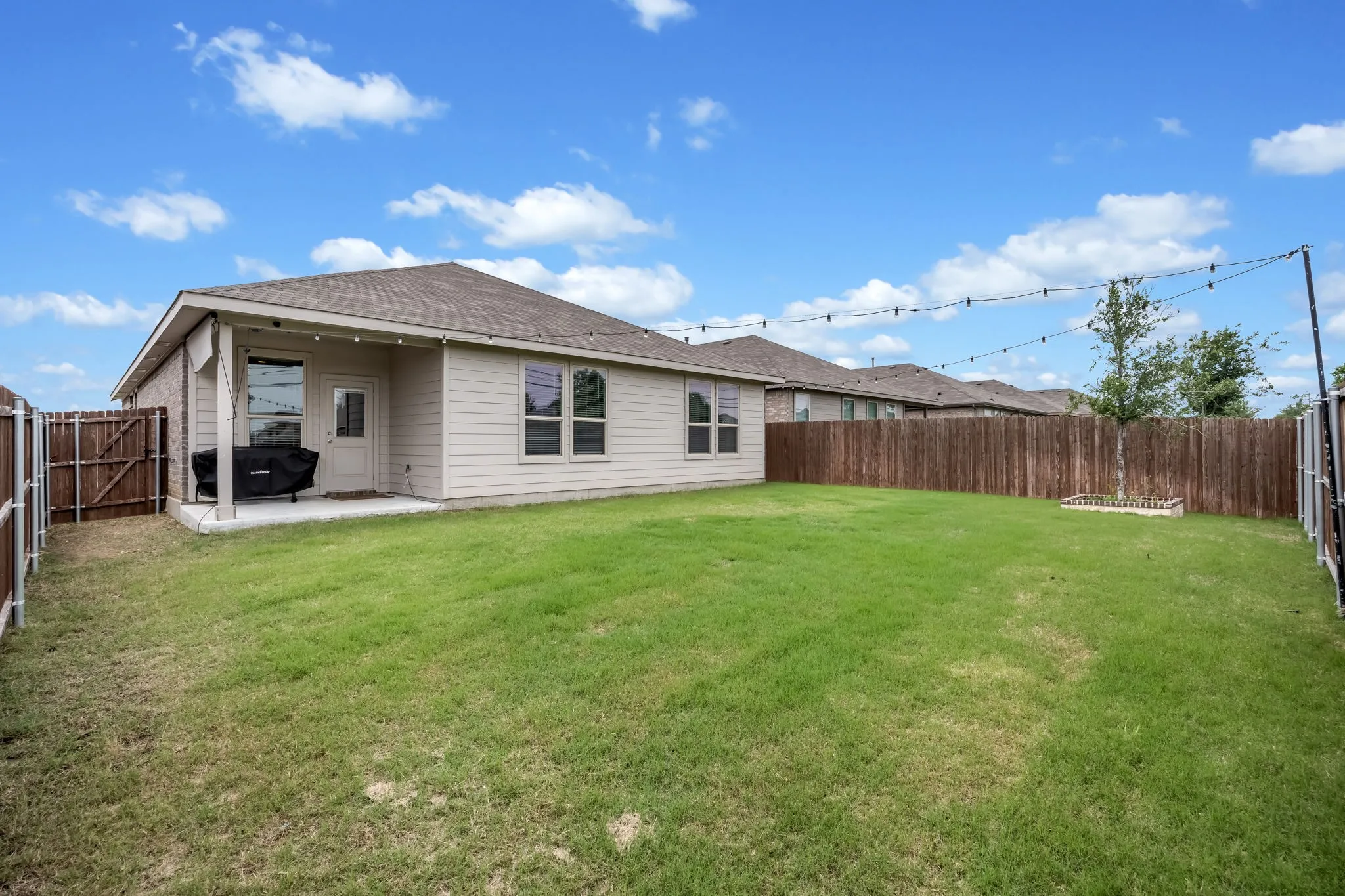 Expansive backyard featuring a manicured lawn, a concrete patio, and a wood privacy fence