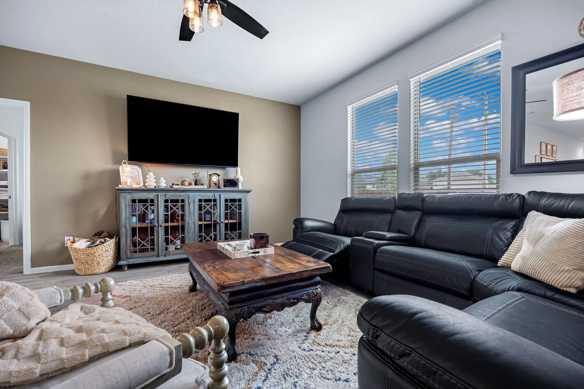 Spacious living area featuring a neutral wall color, ample natural light from multiple windows, and a ceiling fan with integrated lighting