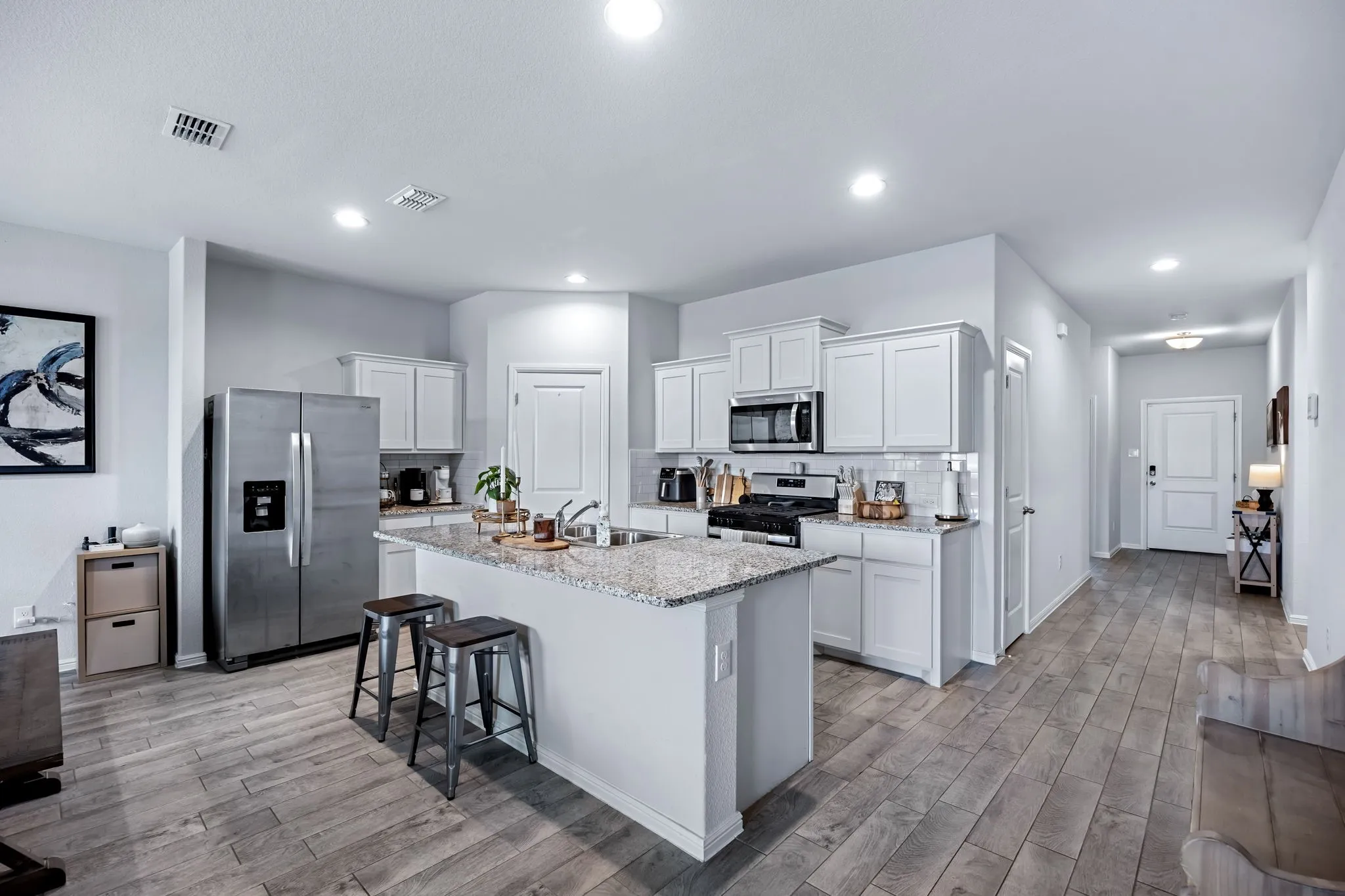 Kitchen featuring a central island with a stone-finish countertop, white cabinetry, and stainless steel appliances
