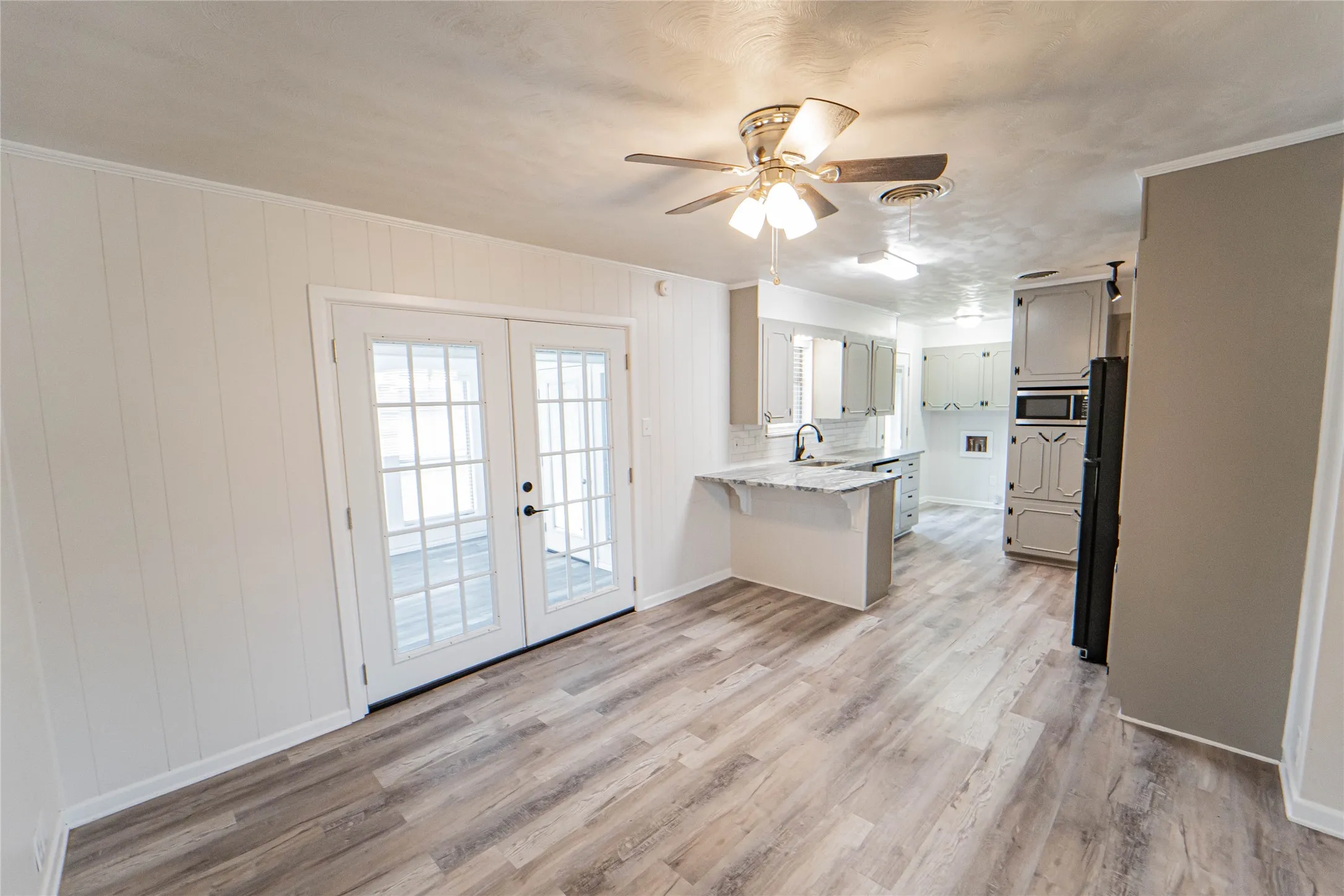 Spacious room, open flow to dining and sunroom- with updated wood-finish flooring and white paneling