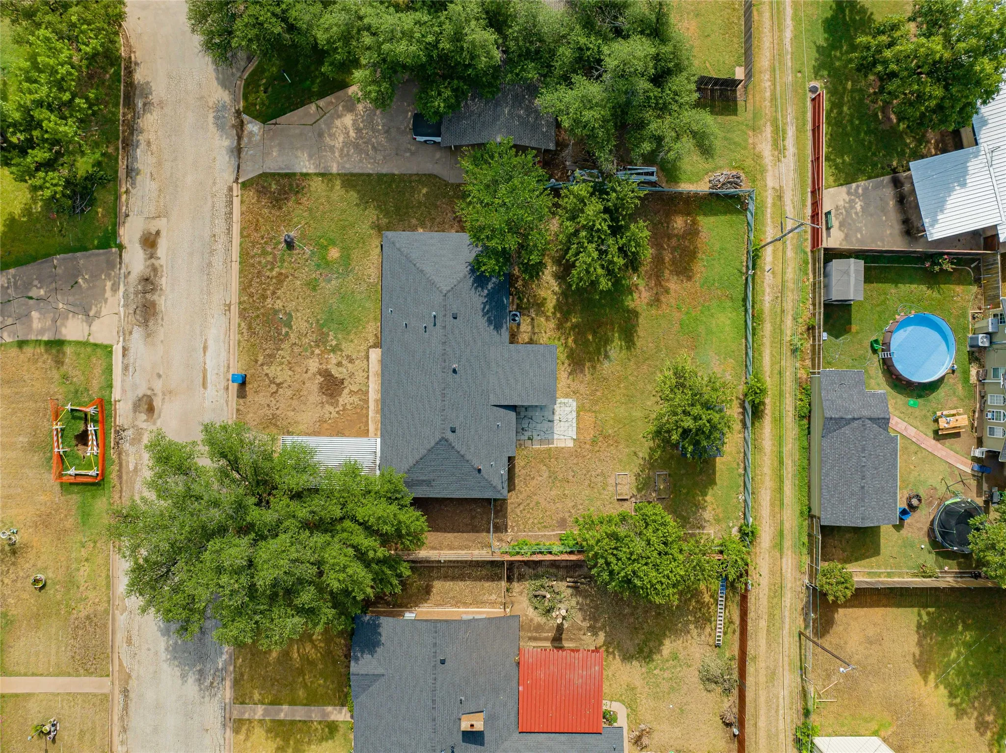 Overhead view showcasing a property with a dark shingle roof and a spacious lawn with mature shade trees and alley access!