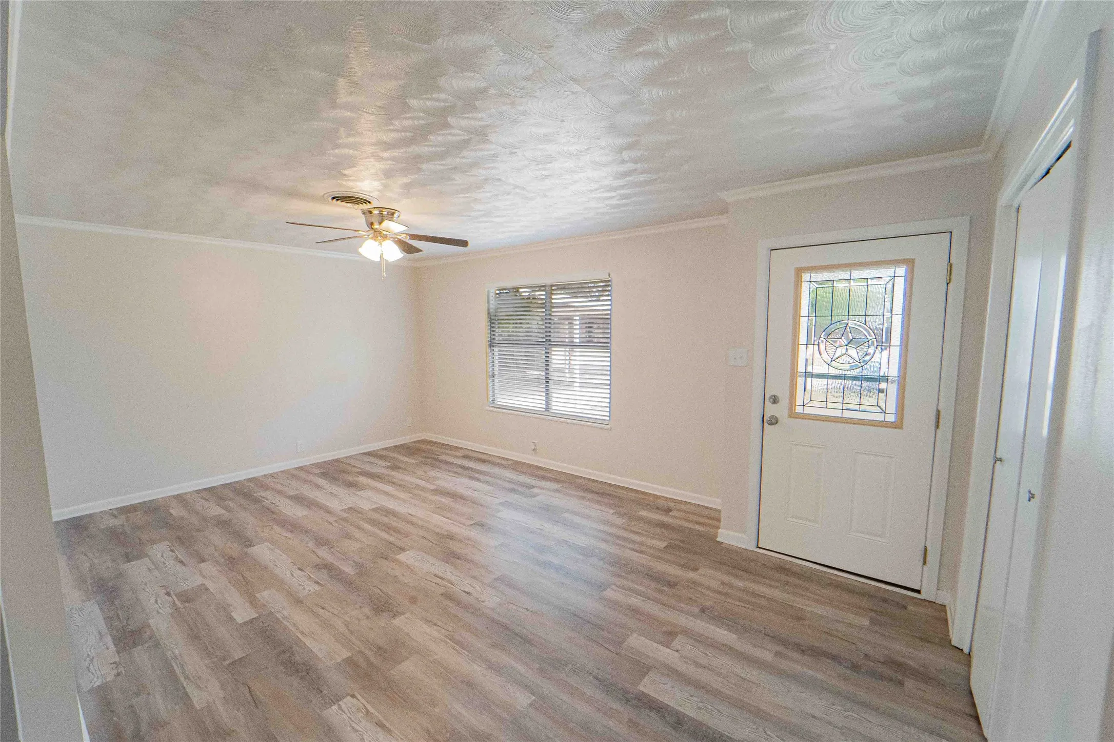 Main living area-Spacious room featuring wood-finish flooring, a ceiling fan, and crown molding