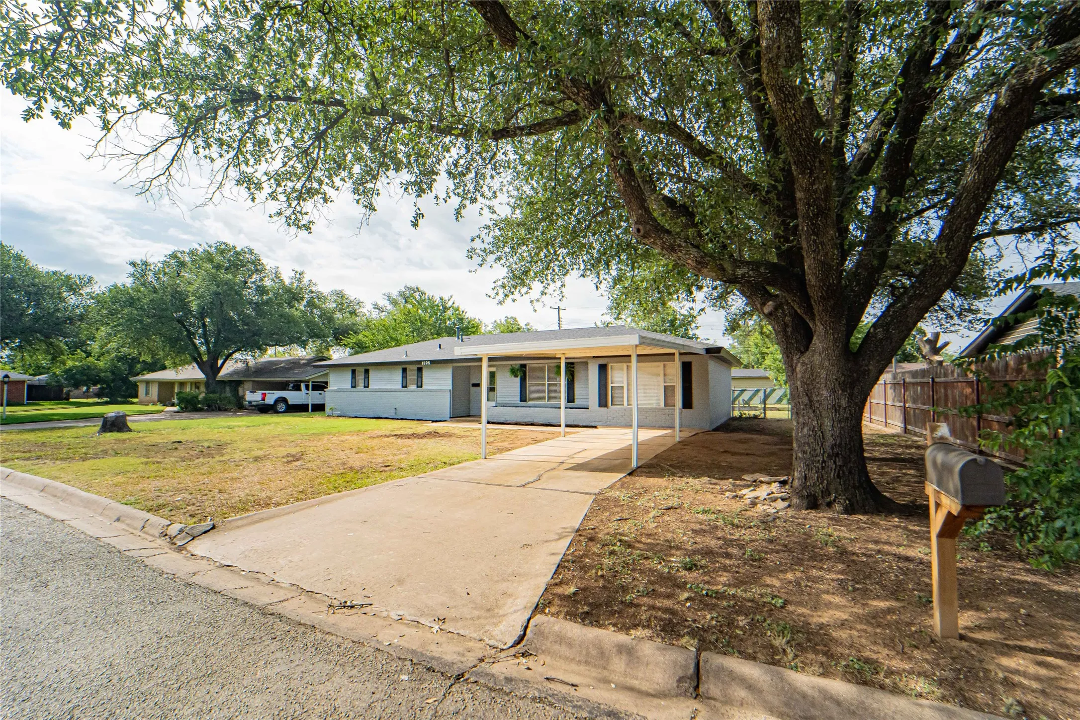 Curbside view-Covered parking and large mature shade tree